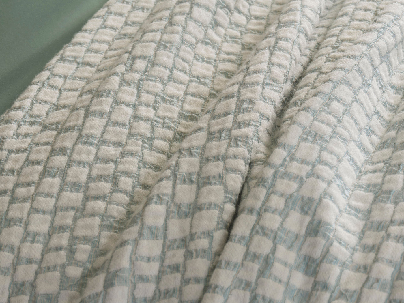 Close-up view of a textured white and pale blue patterned pillow cover, featuring City Pillow Cover by Celso de Lemos available at Linen Society.