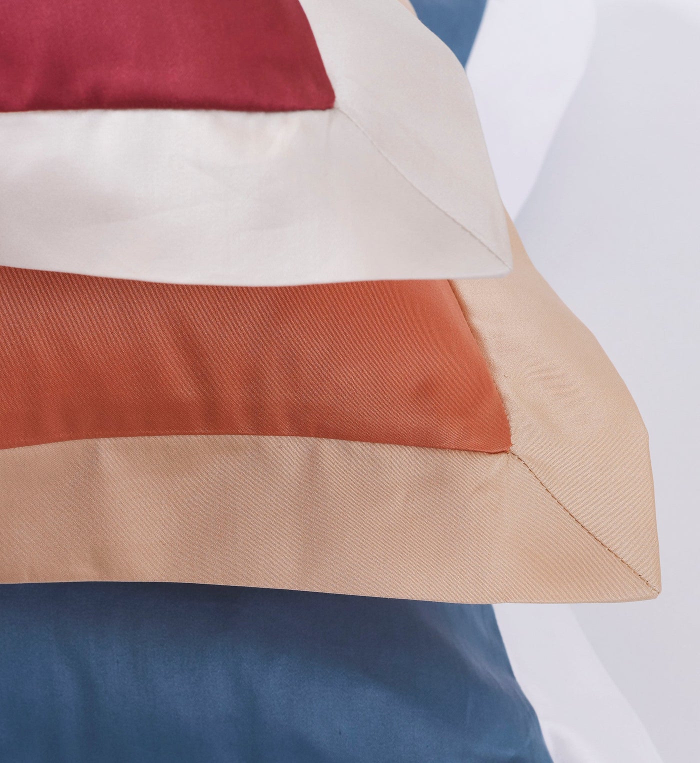 Close-up of striped pillowcases in deep blue, rust orange, and beige, featuring Emma Pillowcase by Celso de Lemos available at Linen Society.
