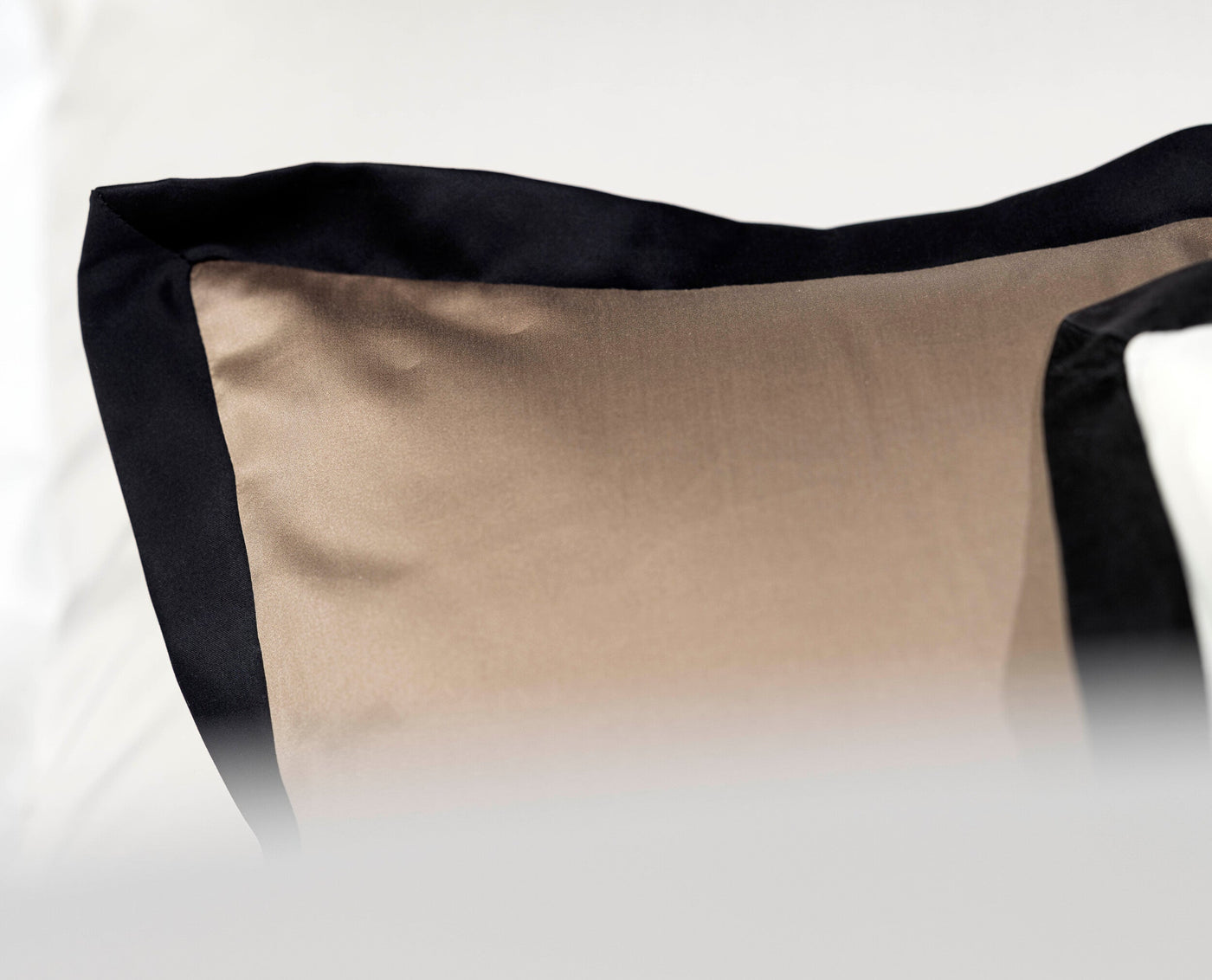 A close-up shot of a pillowcase with a taupe front and black trim, featuring Emma Pillowcase by Celso de Lemos available at Linen Society.