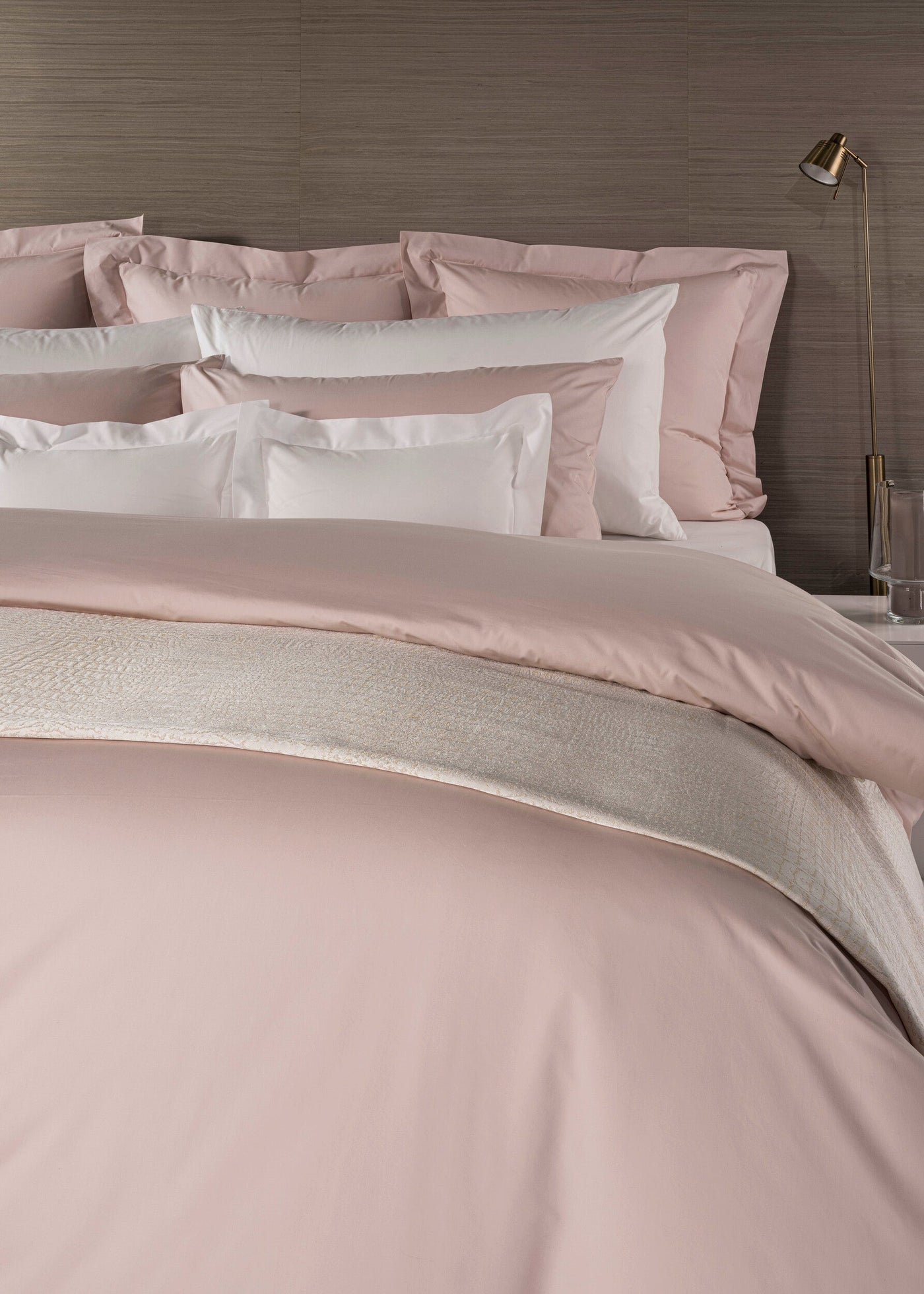 A plush pink duvet and pillows are layered on a bed with a textured accent throw, featuring Estrela Pillowcase by Celso de Lemos available at Linen Society.