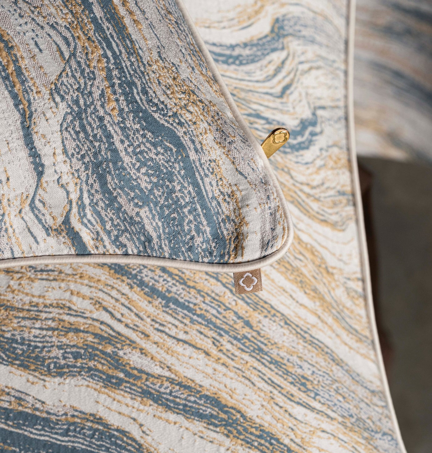 Close-up of textured fabric with a marbled pattern in blue and gold. featuring Filigrane Pillow Cover by Celso de Lemos available at Linen Society.