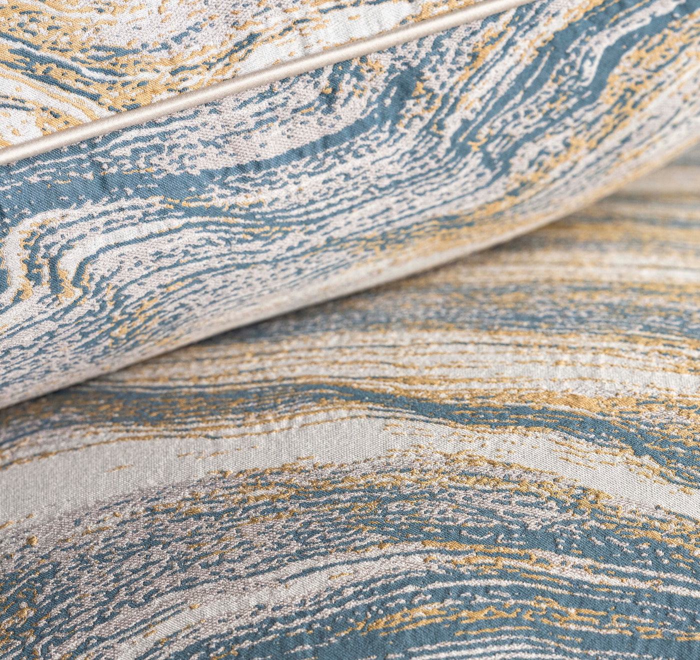 Close-up view of textured fabric with swirling patterns in blue, white, and gold, featuring the Filigrane Pillow Cover by Celso de Lemos available at Linen Society.