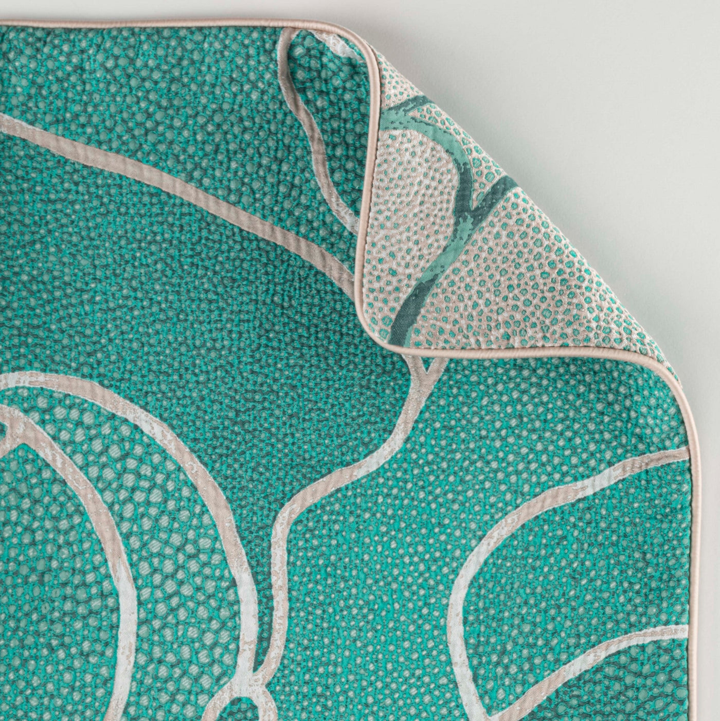 Close-up view of a teal textured fabric with an abstract pattern and cream piping, featuring Funchal Pillow Cover by Celso de Lemos available at Linen Society.
