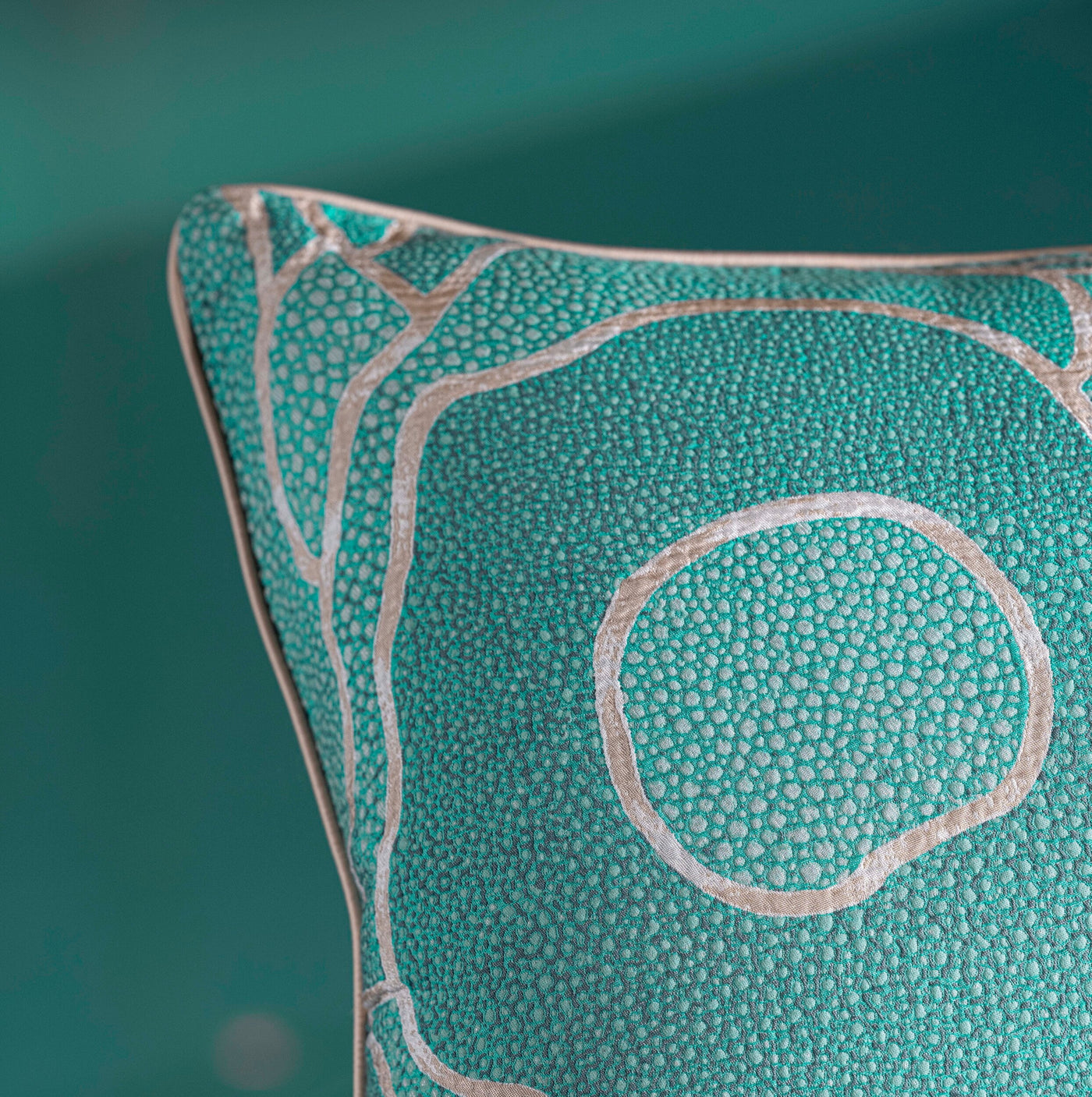 Close-up of a teal pillow with a raised pebble-like texture and a silver outline design, featuring Funchal Pillow Cover by Celso de Lemos available at Linen Society.