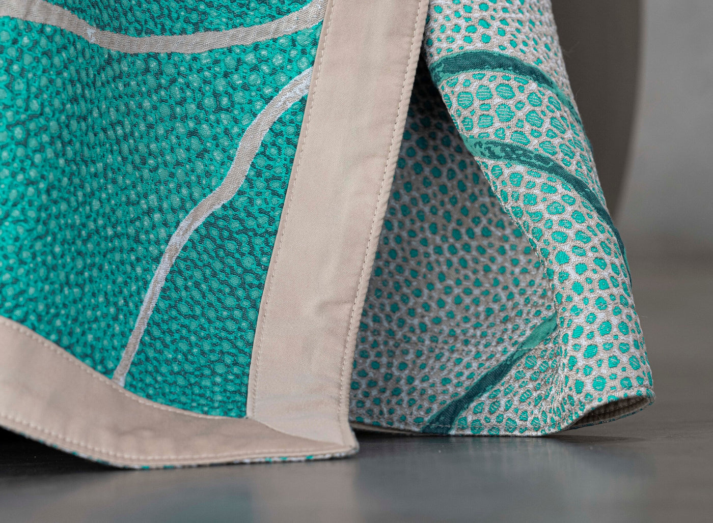 Close-up on a teal and silver patterned pillow cover with a neutral border, featuring Funchal Pillow Cover by Celso de Lemos available at Linen Society.