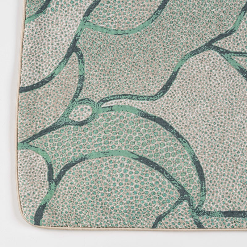 A close-up of a textured fabric with a speckled pattern and abstract green and dark green curvilinear designs. featuring Funchal Pillow Cover by Celso de Lemos available at Linen Society.
