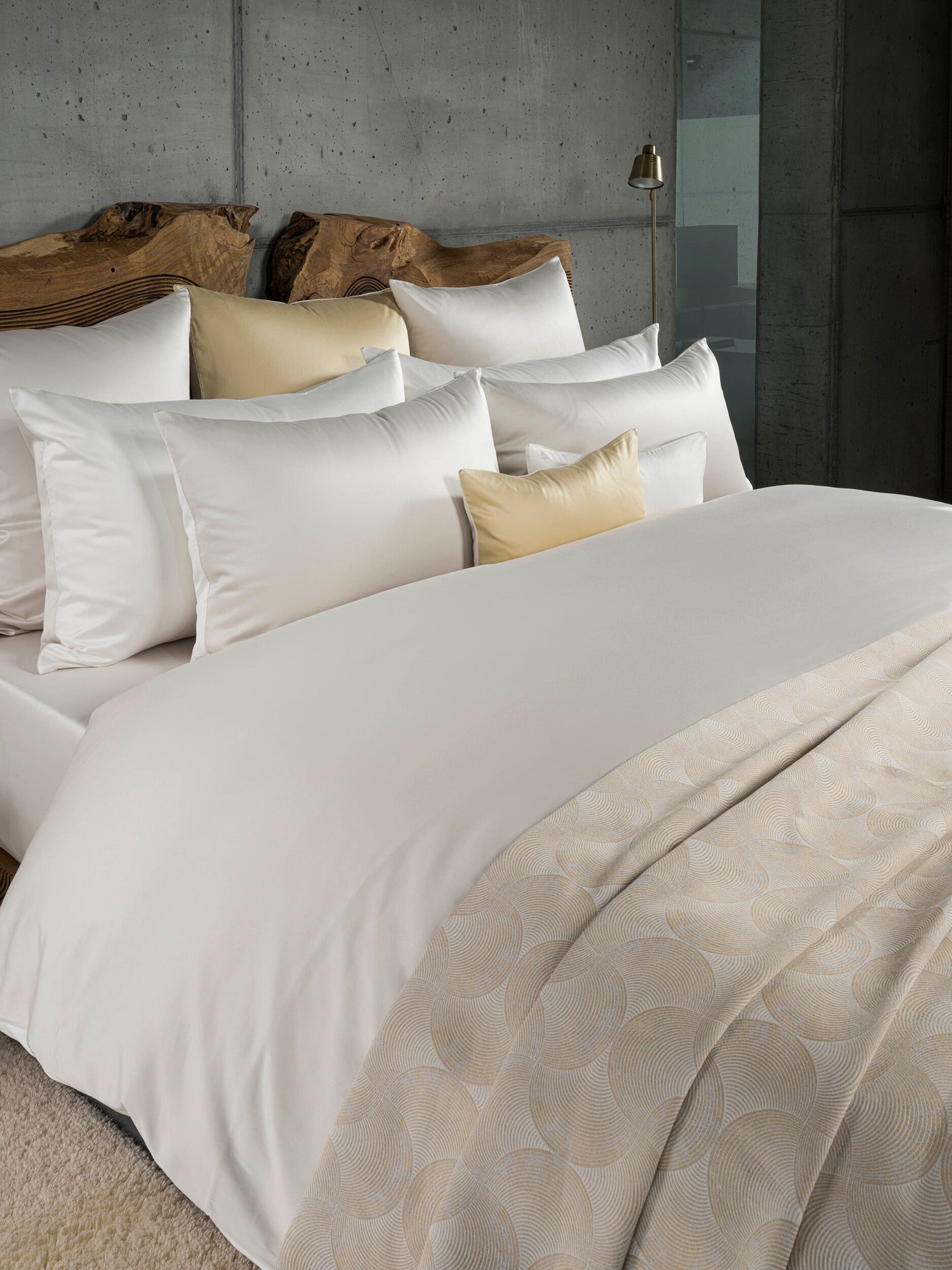 A collection of white and cream bedding and throw with a patterned accent, featuring Gemini Pillowcase by Celso de Lemos available at Linen Society.