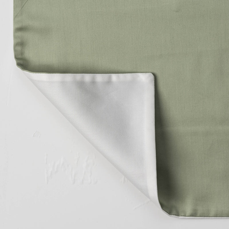 A sage green pillowcase is shown with one corner flipped to reveal a white underside. featuring Gemini Pillowcase by Celso de Lemos available at Linen Society.