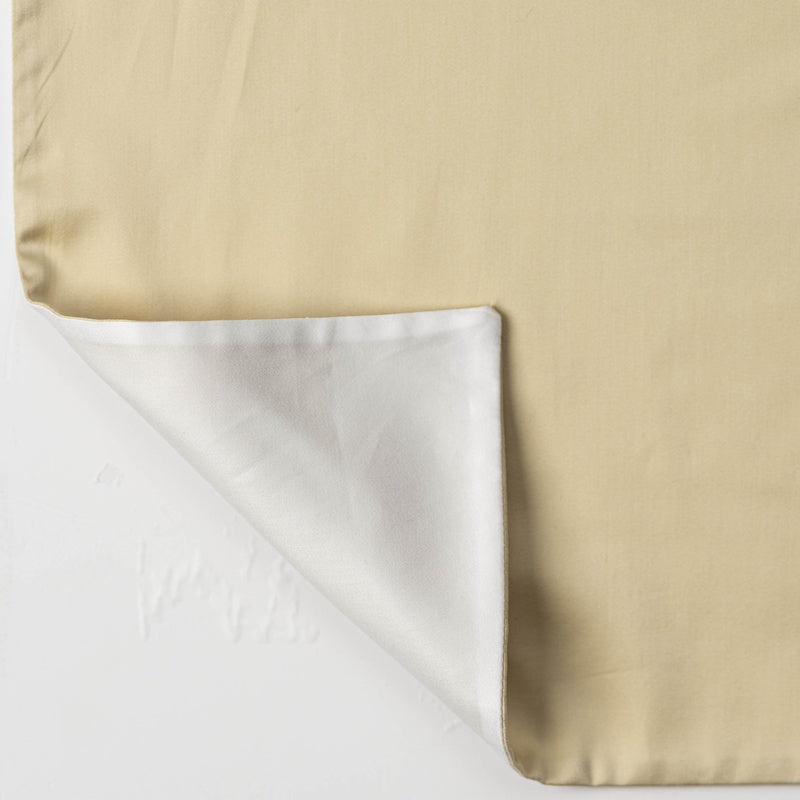 A light beige pillowcase with a white inner lining folded back, featuring Gemini Pillowcase by Celso de Lemos available at Linen Society.