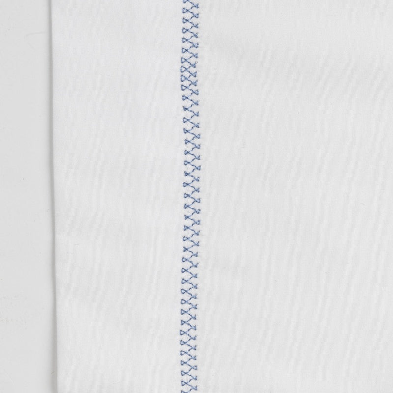 White textile with a thin, vertical row of blue decorative stitching, featuring Ivy Pillowcase by Celso de Lemos available at Linen Society.