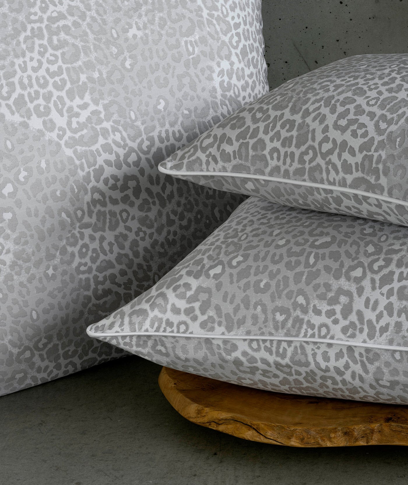 Stack of two grey leopard print pillow covers on a rustic wooden base. featuring Jag Pillow Cover by Celso de Lemos available at Linen Society.