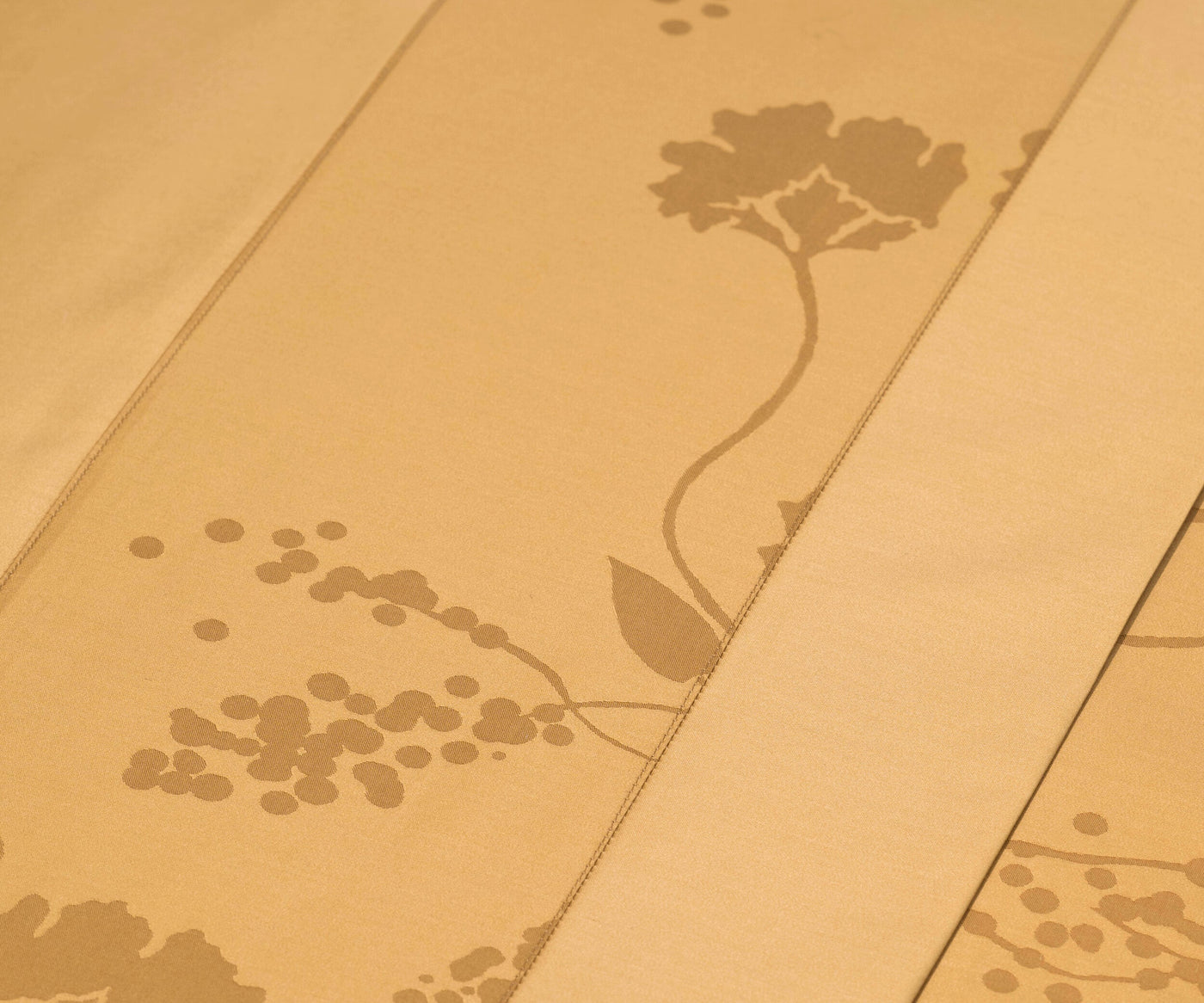 Close-up of a beige fabric with a subtle tonal floral and dot pattern, featuring the Jardim Pillowcase by Celso de Lemos available at Linen Society.