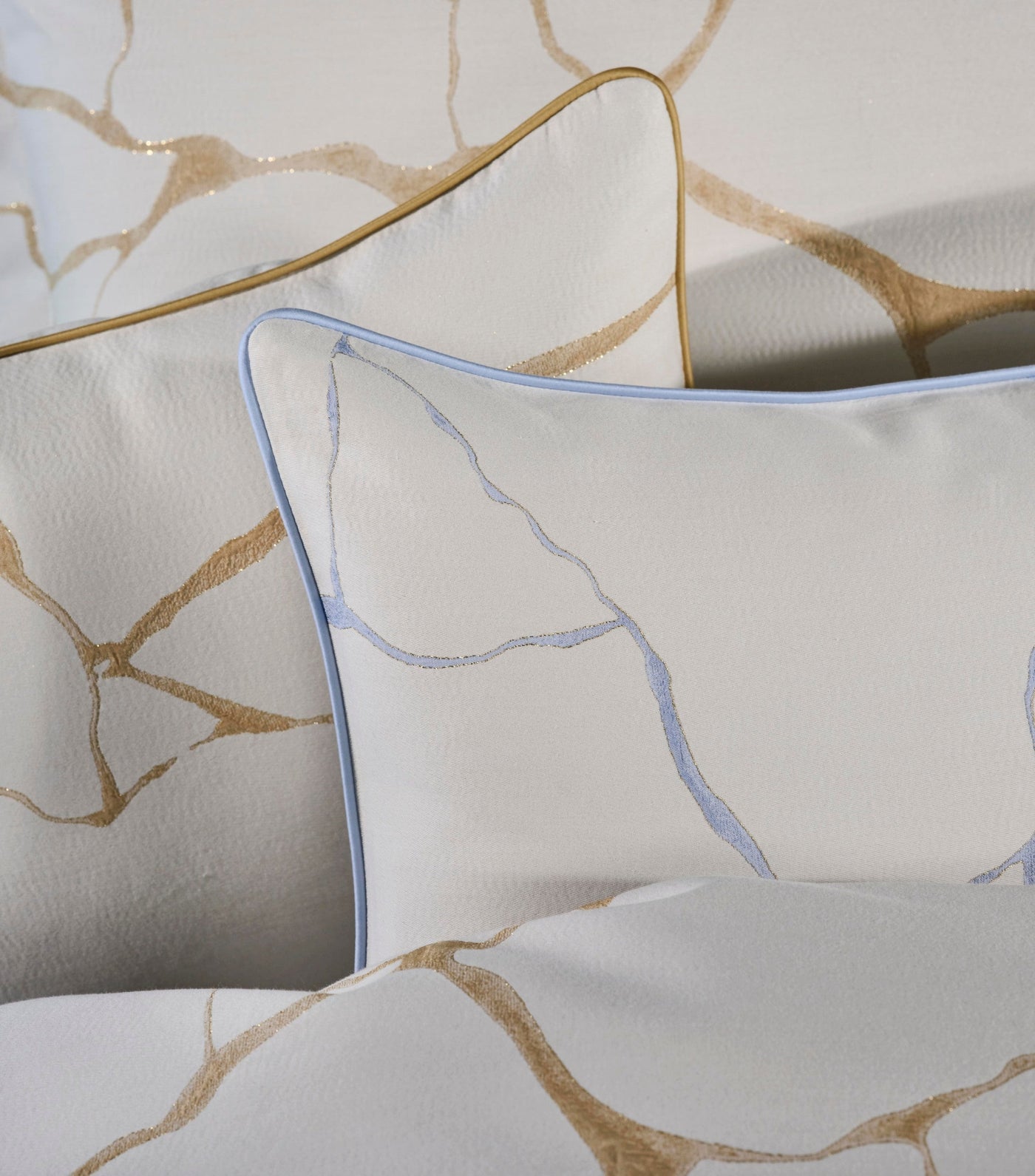 Close-up view of white pillows with a textured pattern of gold and blue lines, featuring Jessie Pillowcase by Celso de Lemos available at Linen Society.
