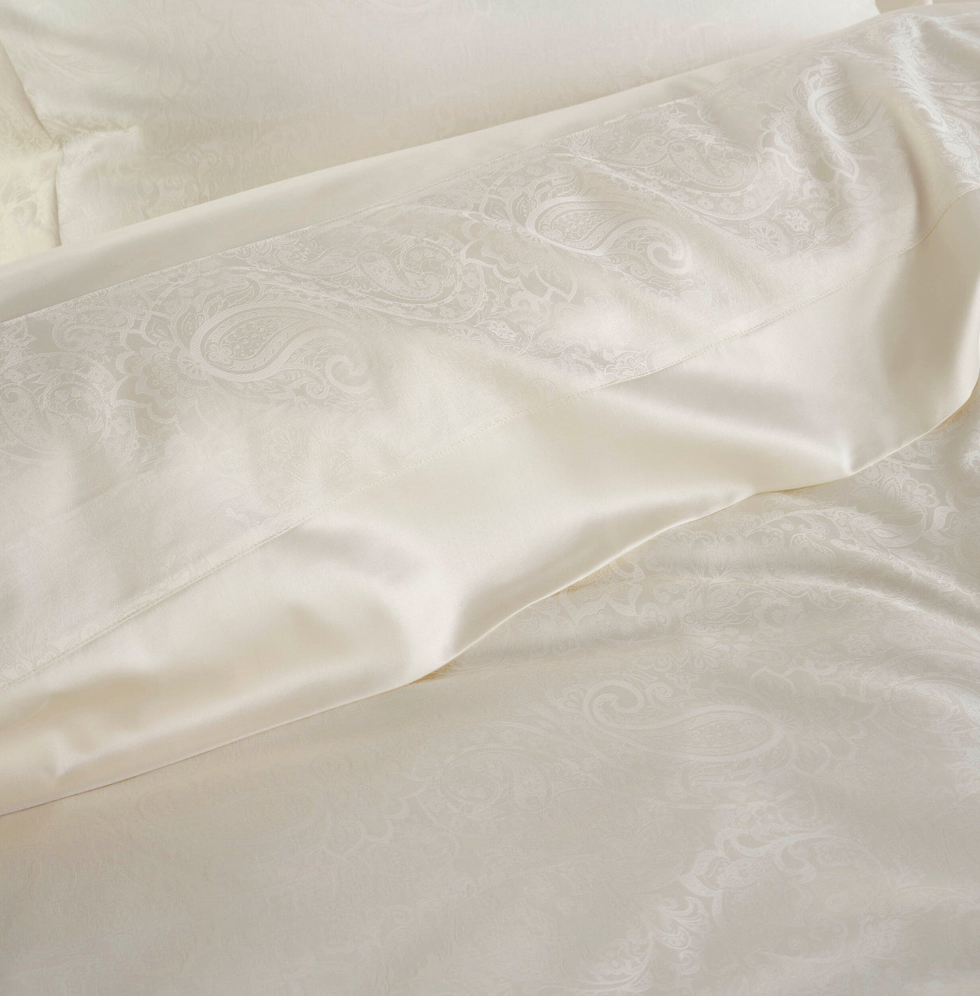 Close-up of a cream jacquard pillowcase with a subtle paisley pattern, featuring Joanne Pillowcase by Celso de Lemos available at Linen Society.