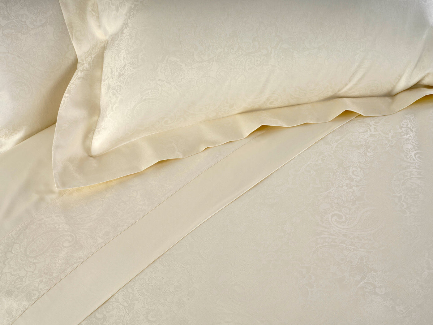 Close-up of a cream-colored duvet cover with an embossed paisley pattern, featuring the Joanne Pillowcase by Celso de Lemos available at Linen Society.