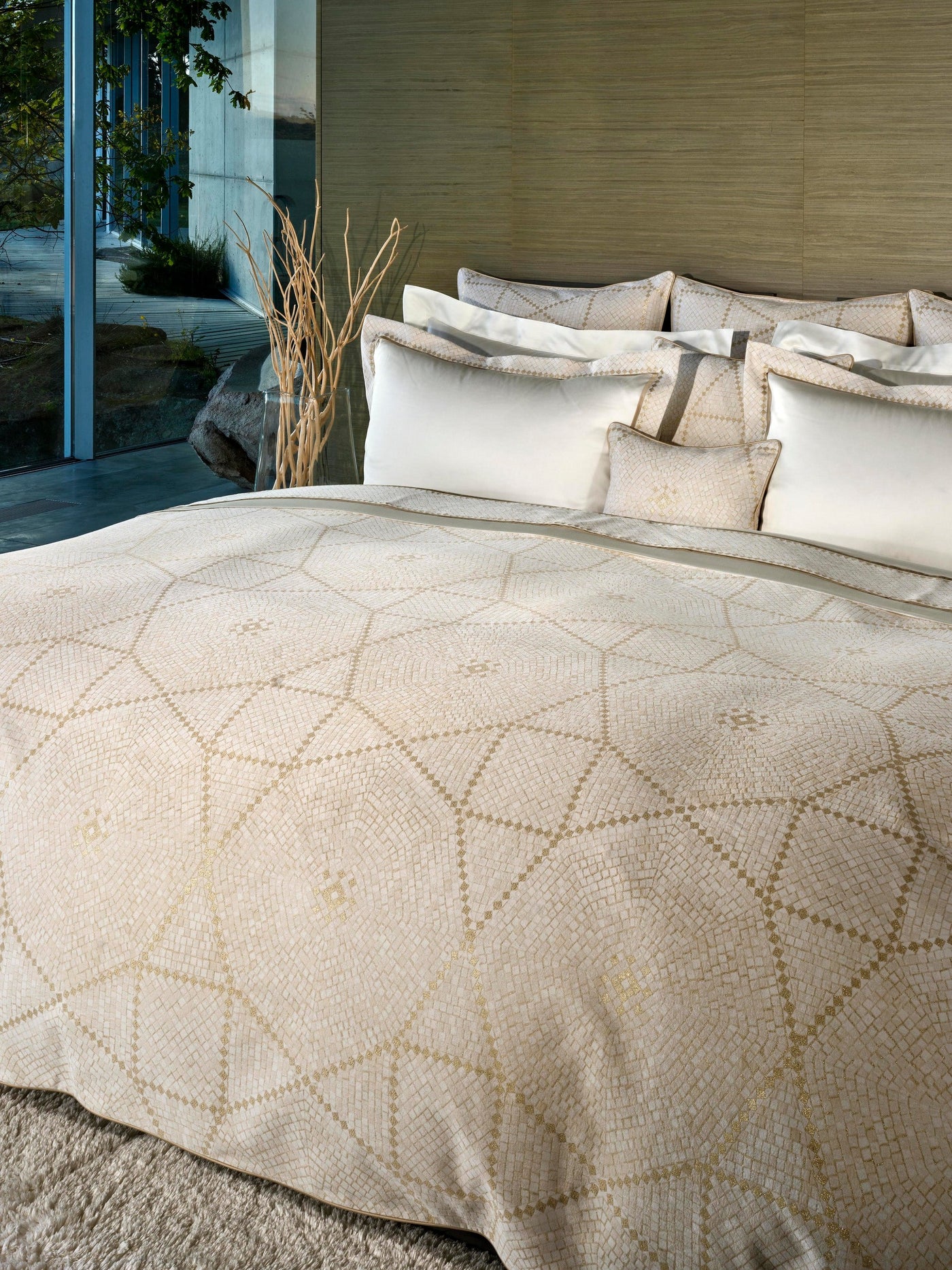 A close-up of a bed with a mosaic-patterned duvet and white pillows, featuring Kerylos Pillowcase by Celso de Lemos available at Linen Society.
