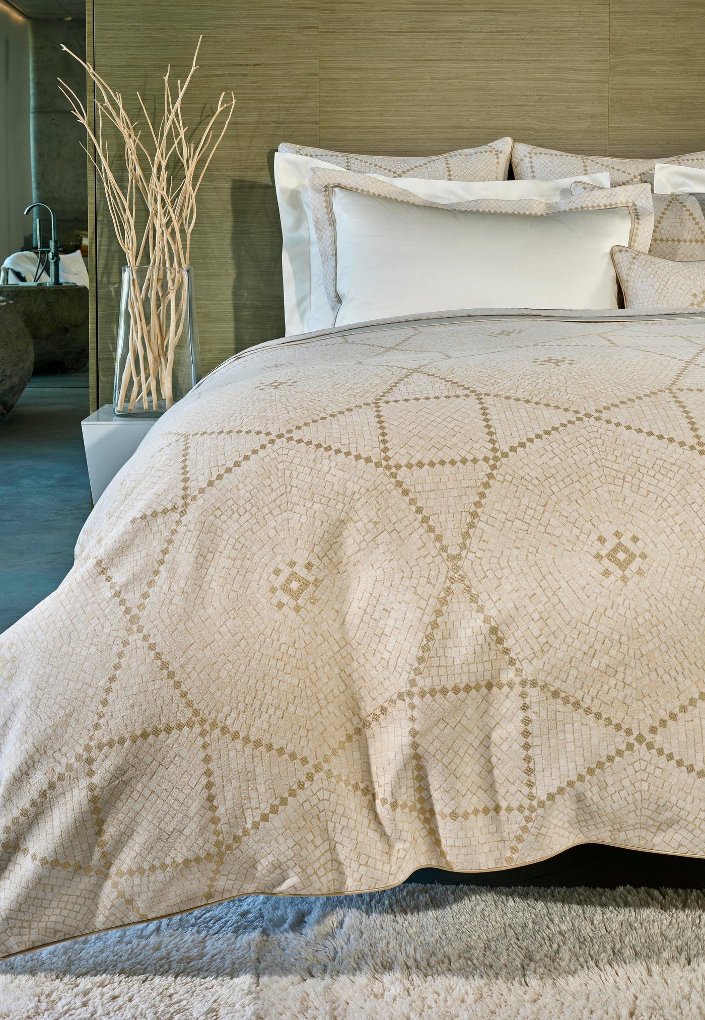 A bed draped with a cream-colored duvet featuring a geometric pattern in a slightly darker cream. Featuring Kerylos Pillowcase by Celso de Lemos available at Linen Society.