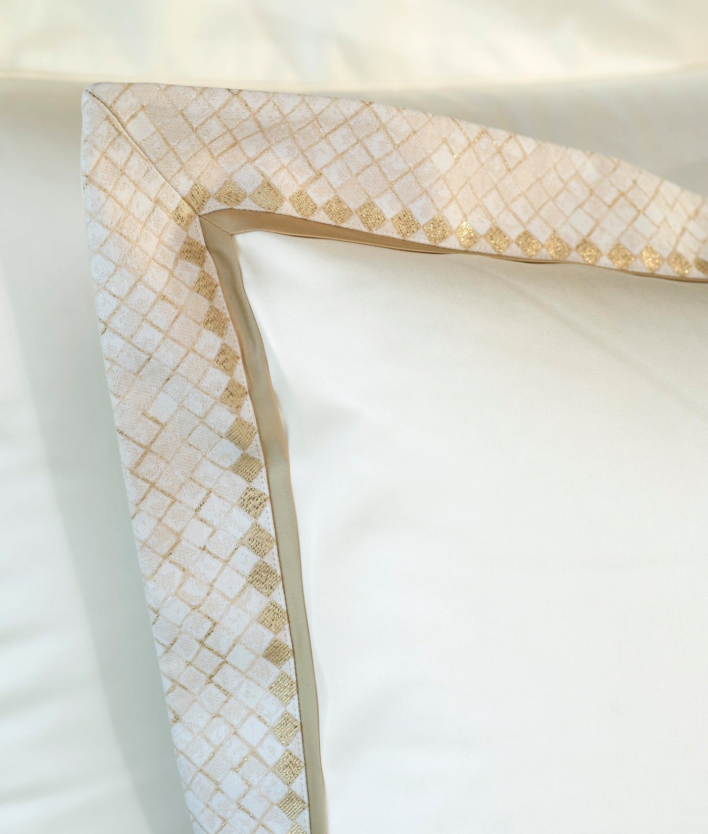 A close-up of a white pillowcase with a textured golden geometric border. featuring Kerylos Pillowcase by Celso de Lemos available at Linen Society.