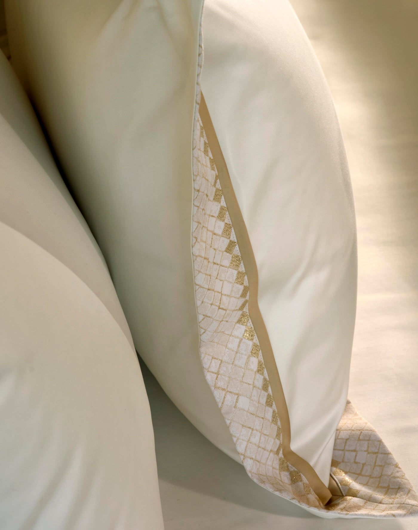 Two off-white pillows with a subtle diamond pattern and gold metallic thread accent, featuring Kerylos Pillowcase by Celso de Lemos available at Linen Society.