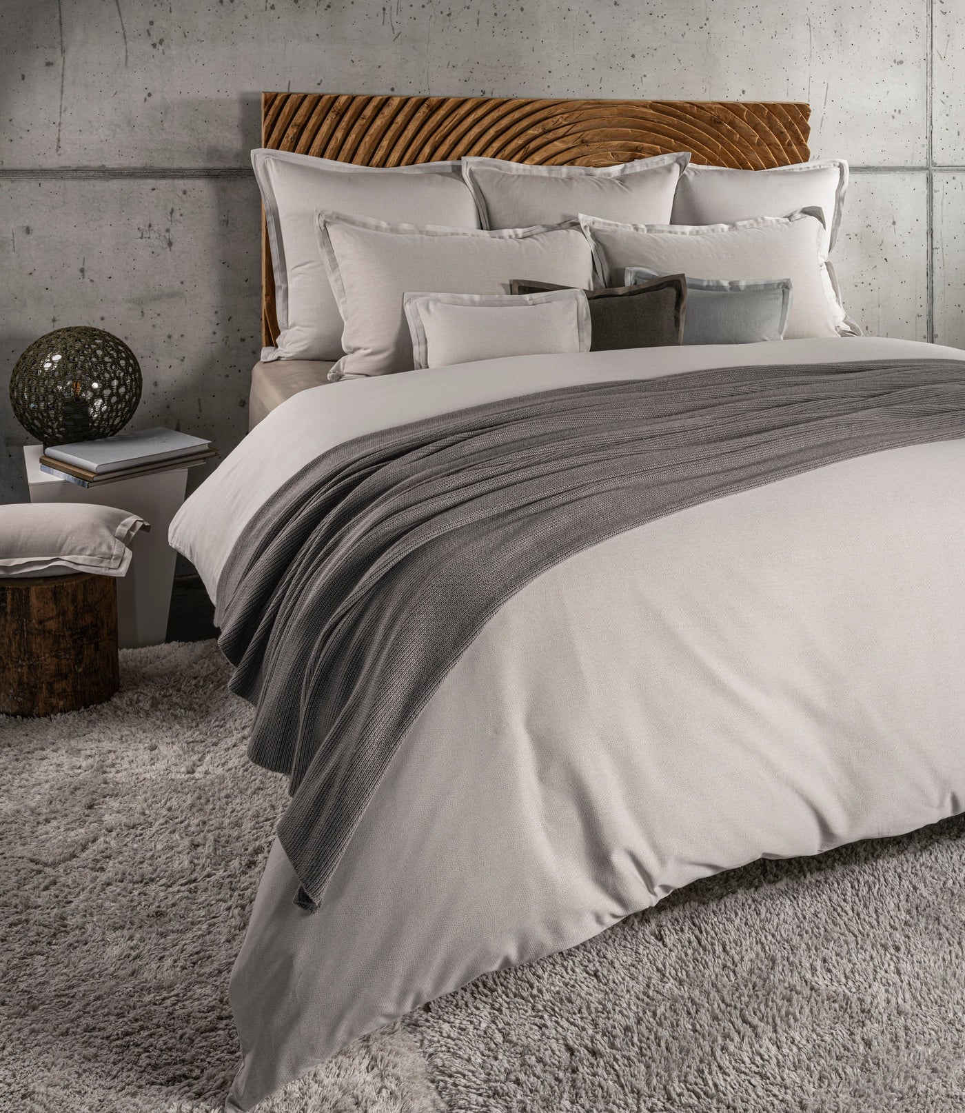 A collection of plush pillows and a duvet with a textured throw are arranged on a bed. Featuring Kroco Pillowcase by Celso de Lemos available at Linen Society.