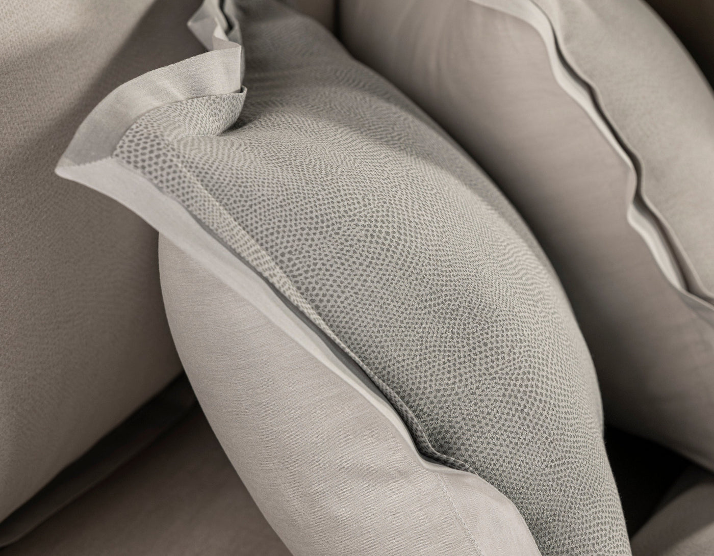 Close-up of textured grey pillowcases arranged on a sofa, featuring Kroco Pillowcase by Celso de Lemos available at Linen Society.