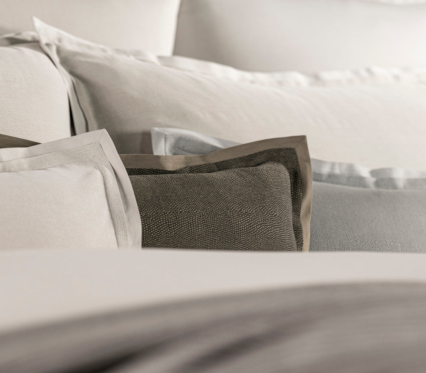 Close-up of layered pillows with textured fabric details, featuring Kroco Pillowcase by Celso de Lemos available at Linen Society.