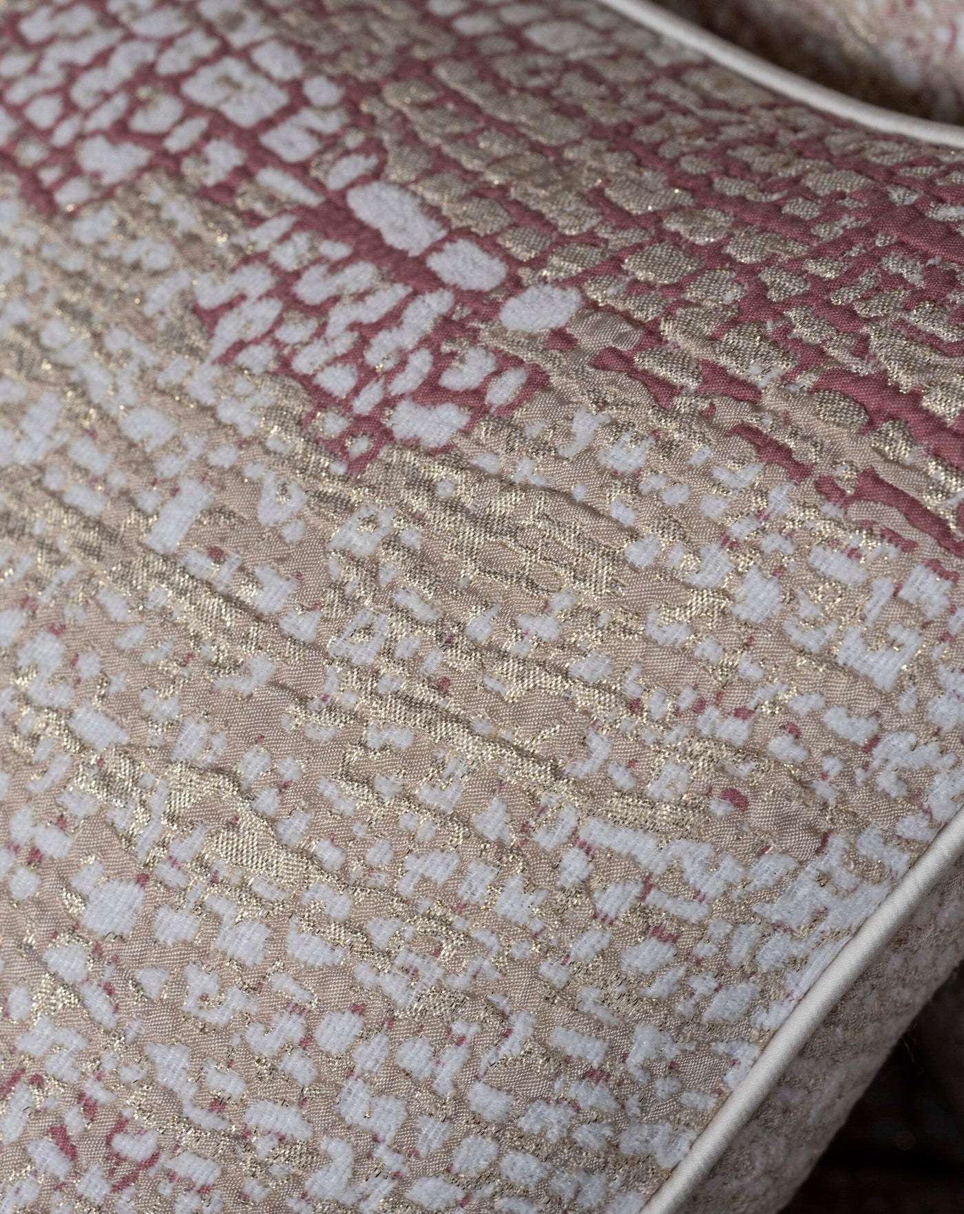 Close-up of textured fabric with a rose, white, and metallic gold abstract pattern, featuring Lems Pillow Cover by Celso de Lemos available at Linen Society.
