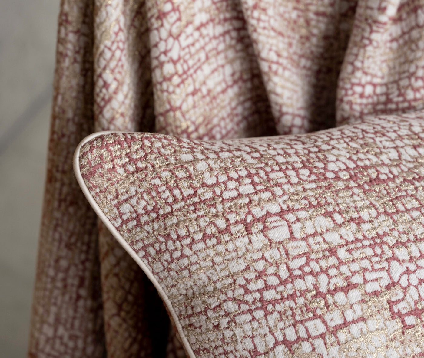 Close-up of a textured pillow cover with a pink and gold abstract pattern, featuring the Lems Pillow Cover by Celso de Lemos available at Linen Society.