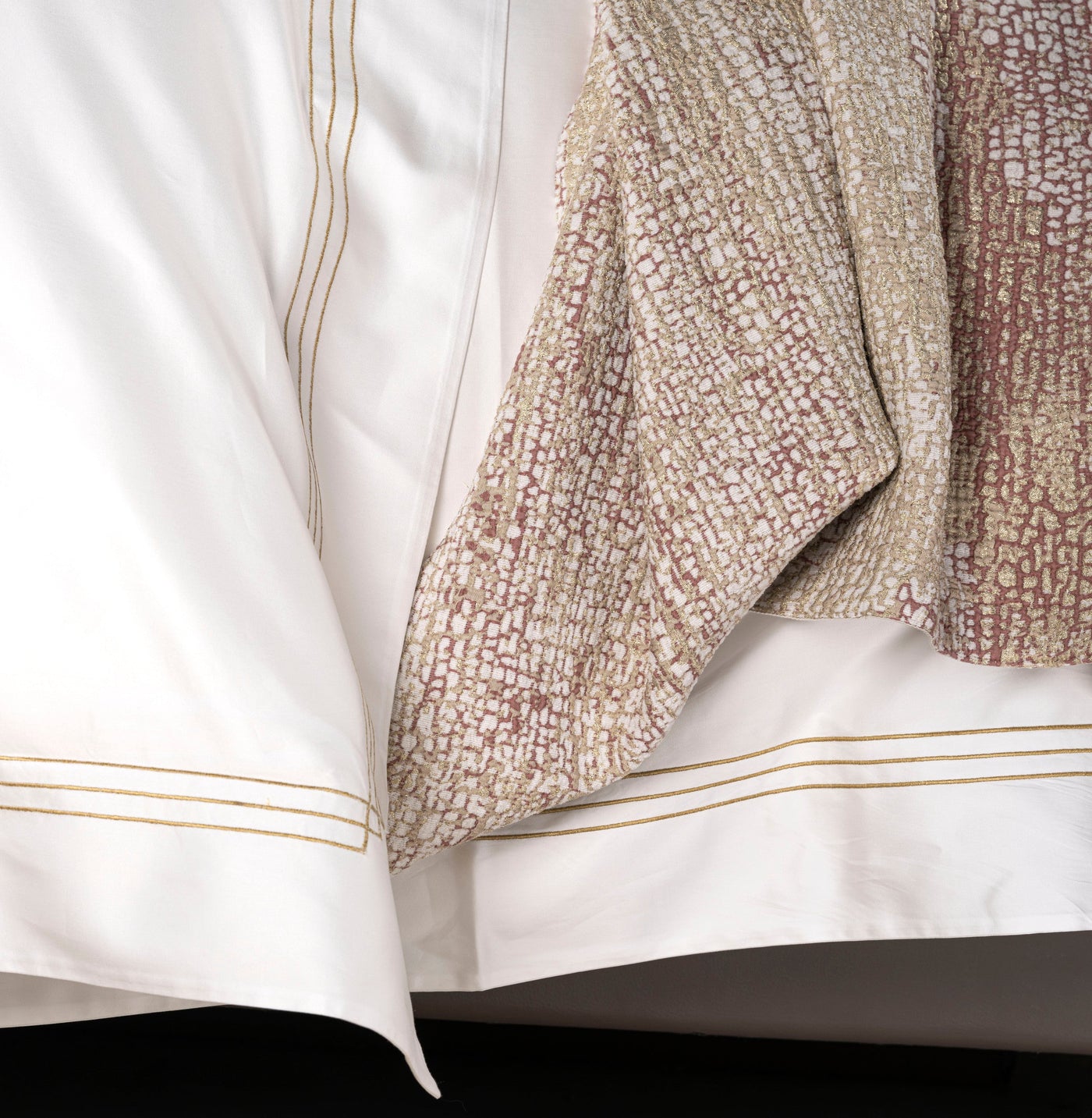 White fabric with gold stitching and a textured, patterned fabric in tones of white, gold, and rust. featuring Lems Pillow Cover by Celso de Lemos available at Linen Society.