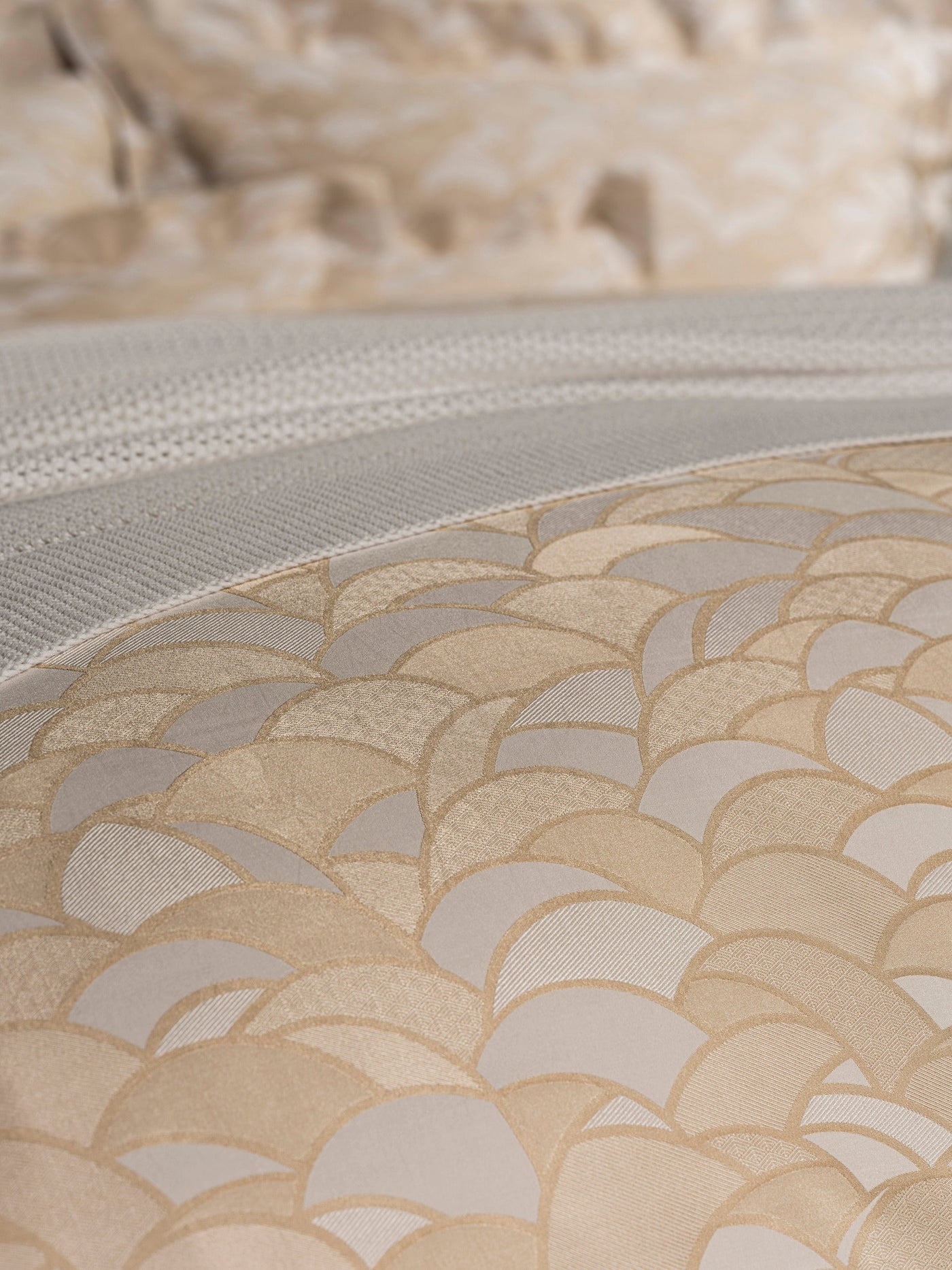 Close-up of a bed with a textured neutral duvet cover featuring a fan-like pattern and a woven textured throw blanket, featuring Loulou Duvet Cover by Celso de Lemos available at Linen Society.