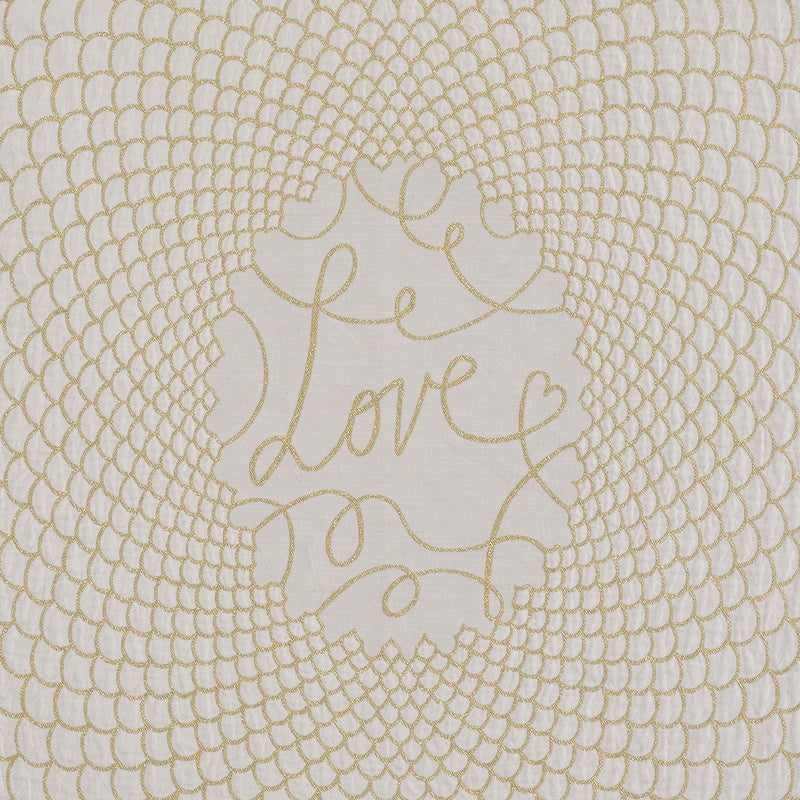 Close-up of white fabric with a gold embroidered circular pattern and the word "Love" in gold script, featuring Love Pillow Cover by Celso de Lemos available at Linen Society.
