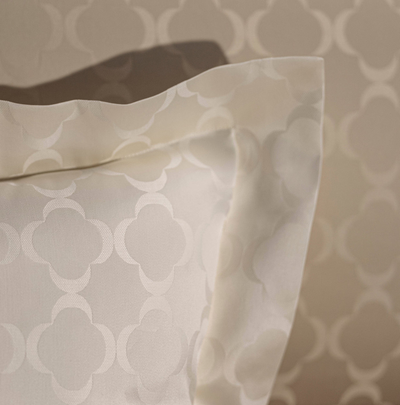Close-up of a cream-colored pillowcase with a subtle geometric pattern, featuring Lua Pillowcase by Celso de Lemos available at Linen Society.