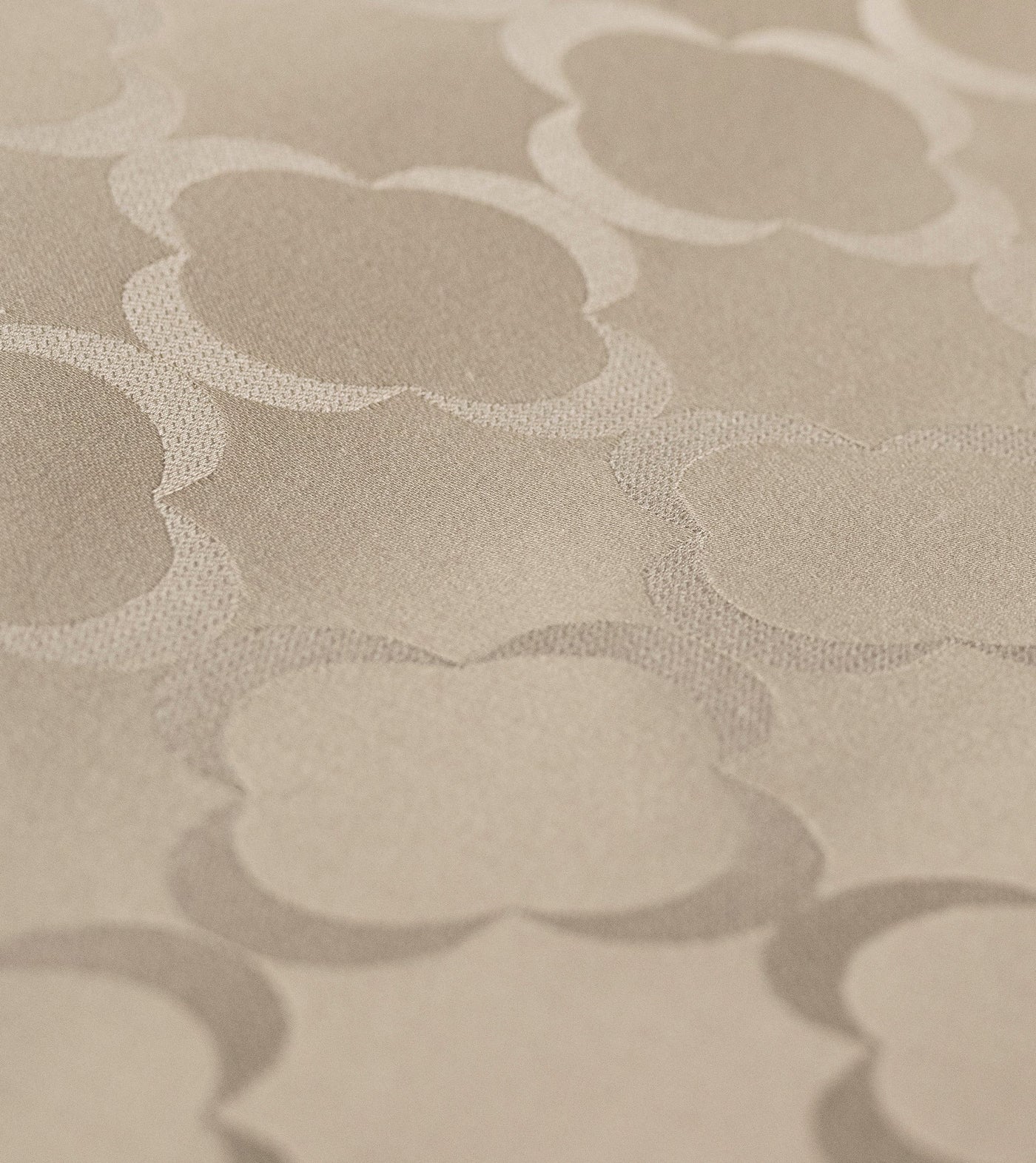 Close-up of a light beige fabric with a raised quatrefoil pattern, featuring Lua Pillowcase by Celso de Lemos available at Linen Society.