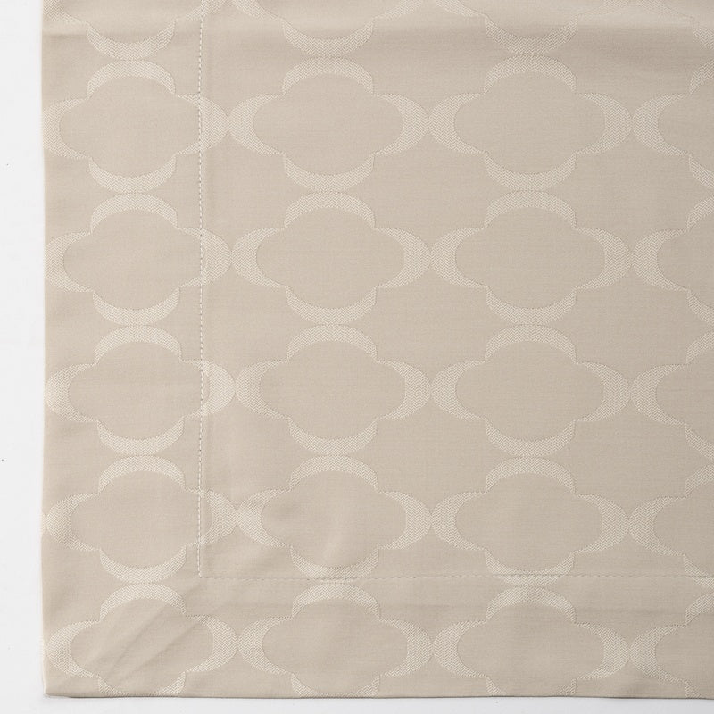 Close-up of a beige fabric with a subtle raised clover-like pattern, featuring Lua Pillowcase by Celso de Lemos available at Linen Society.