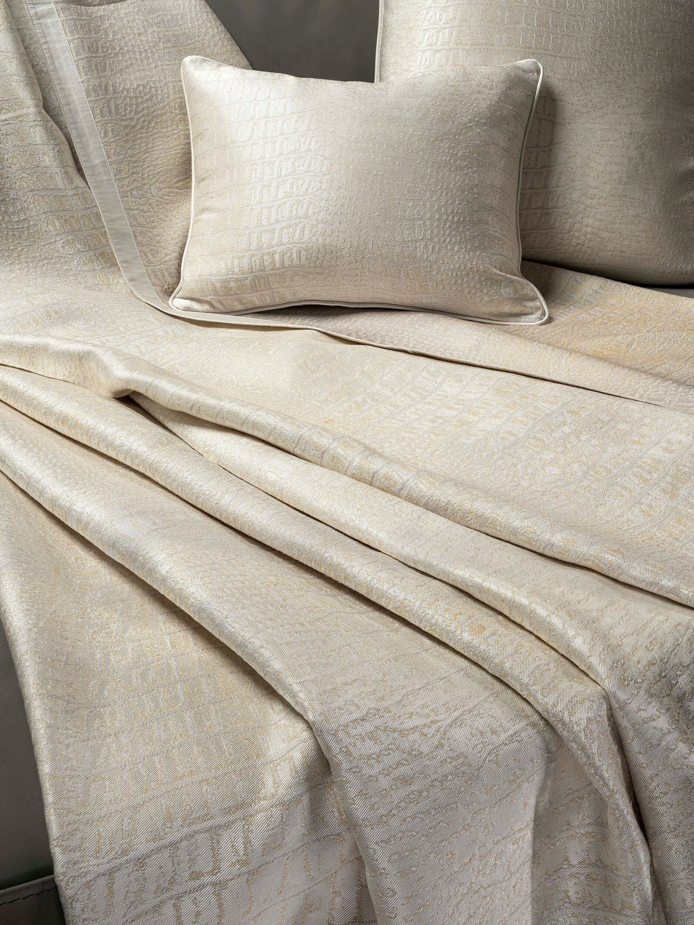 Close-up of luxurious textured champagne-colored textiles folded and layered, featuring the Luxe Pillow Cover by Celso de Lemos available at Linen Society.