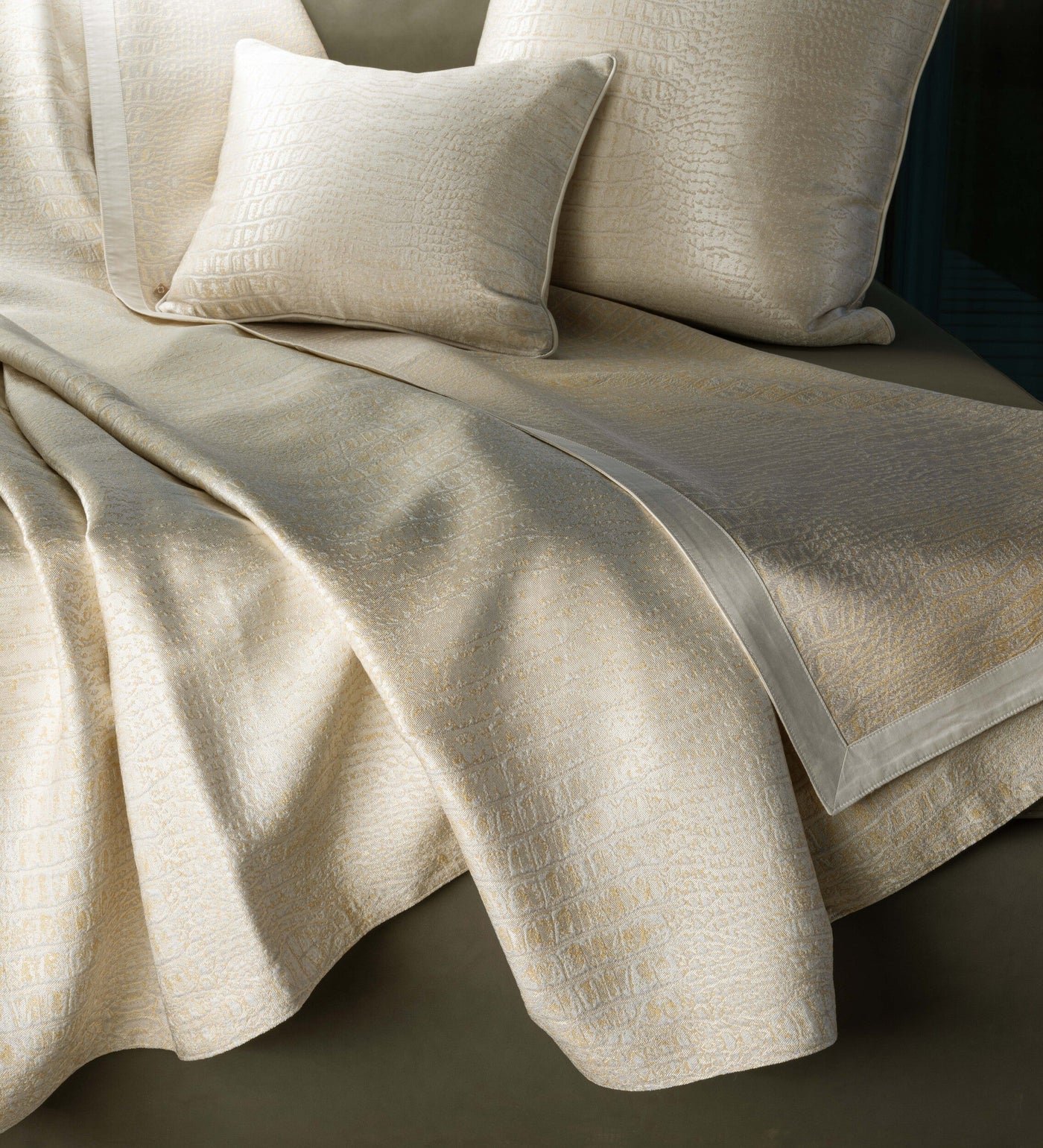 A light beige textured pillow and folded fabric are artfully arranged. featuring Luxe Pillow Cover by Celso de Lemos available at Linen Society.