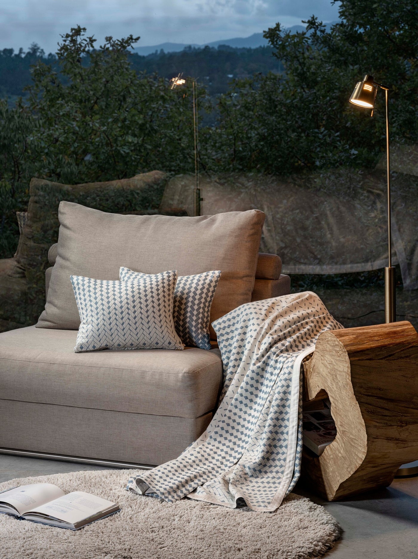 A neutral-toned sofa displays two patterned accent pillows and a throw. featuring Marbella Pillow Cover by Celso de Lemos available at Linen Society.
