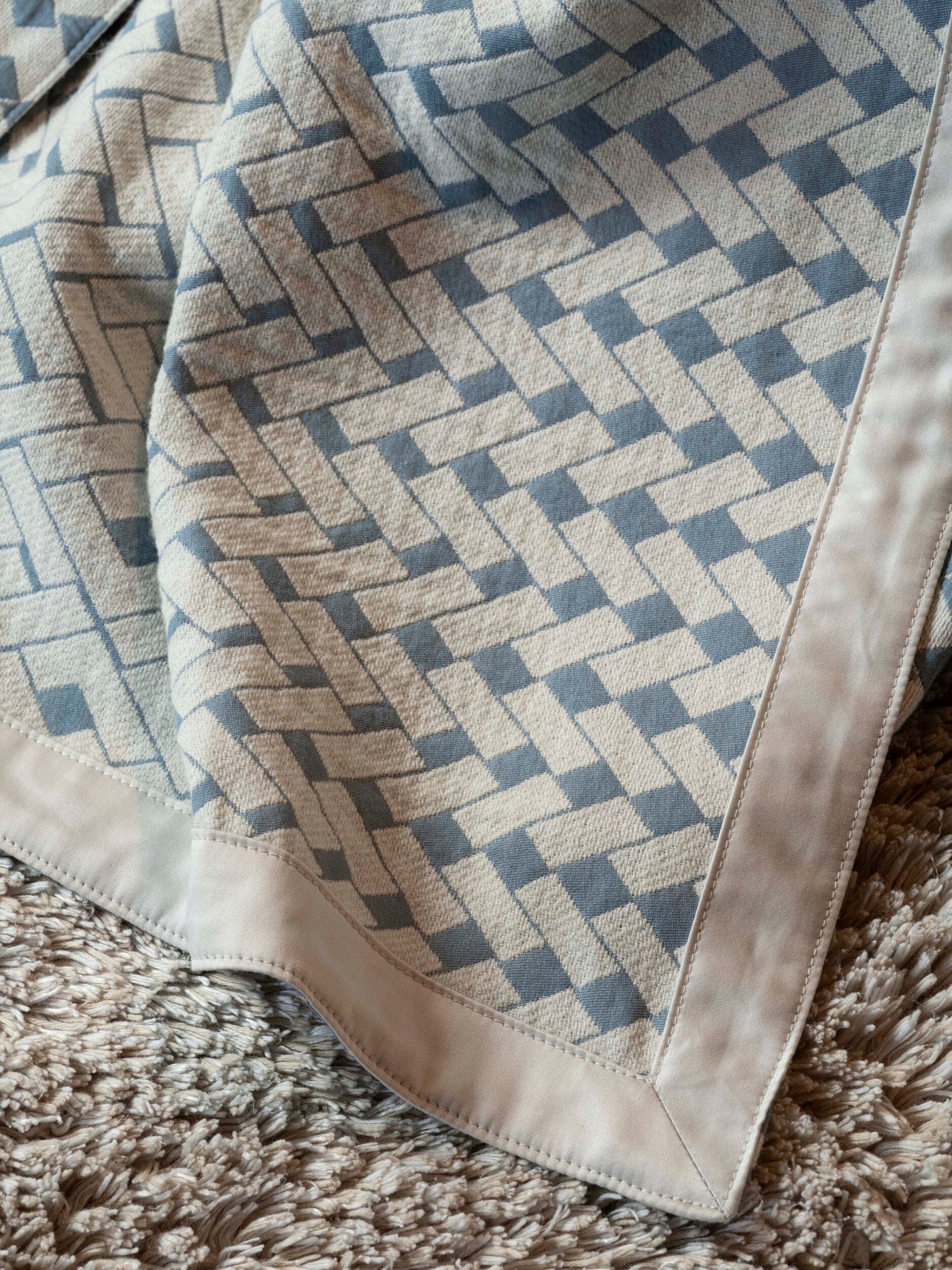 Close-up of a textured fabric with a geometric blue and cream pattern, featuring the Marbella Pillow Cover by Celso de Lemos available at Linen Society.