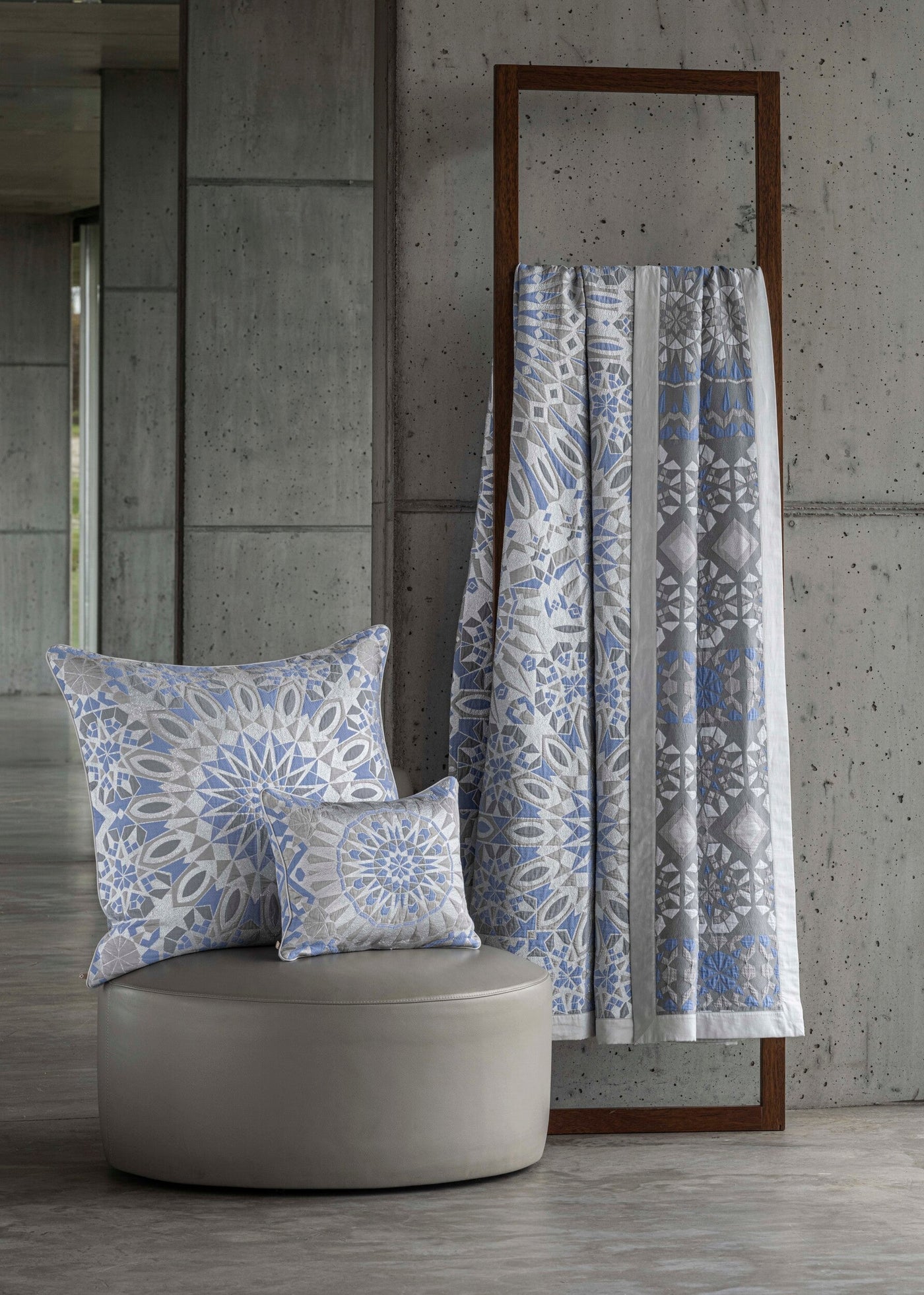 Pillows and a draped blanket showcase intricate geometric patterns in blue and grey hues. featuring Milena Pillow Cover by Celso de Lemos available at Linen Society.