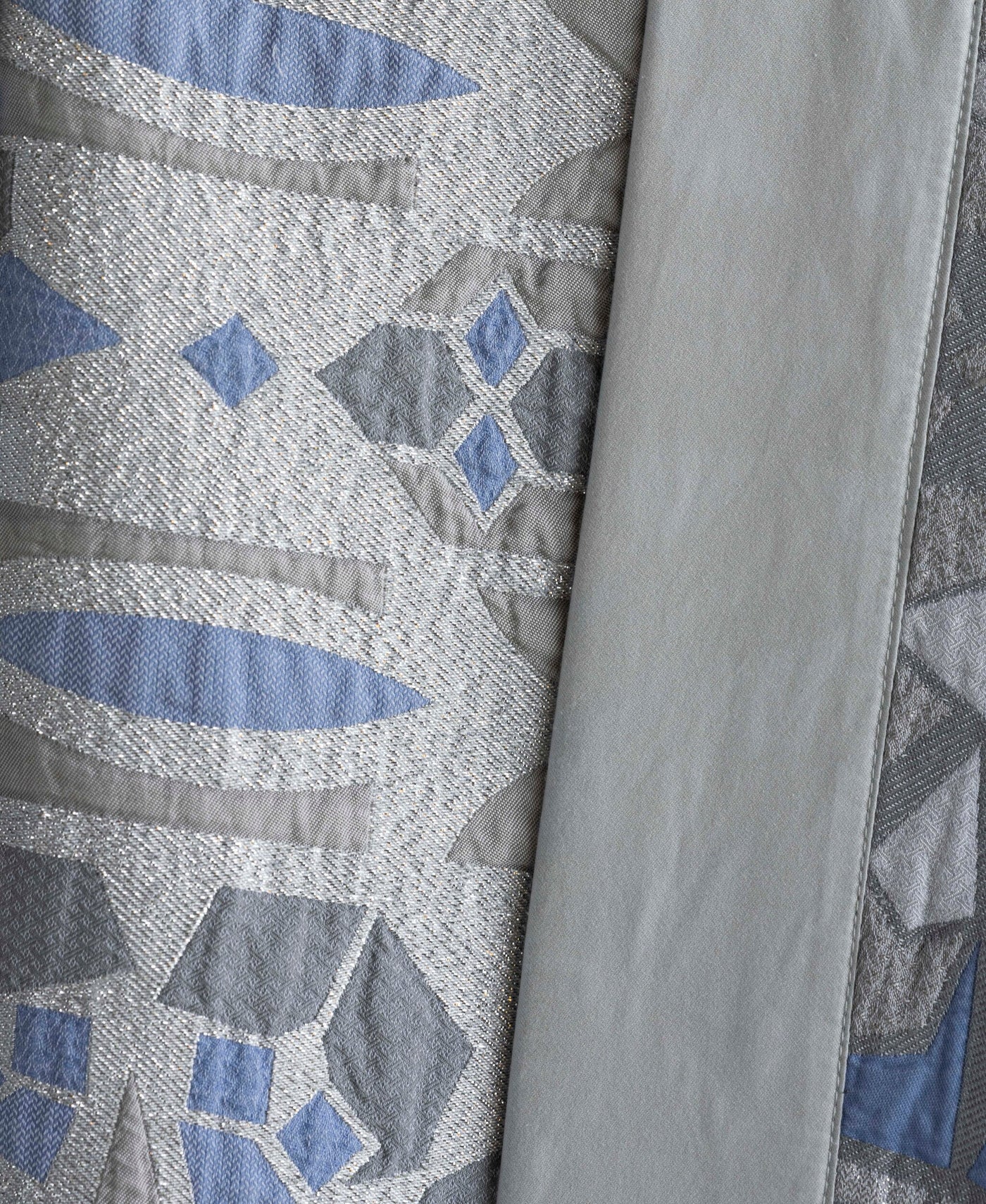 Close-up of a fabric with a geometric pattern of blue, grey, and silver threads, featuring the Milena Pillow Cover by Celso de Lemos available at Linen Society.