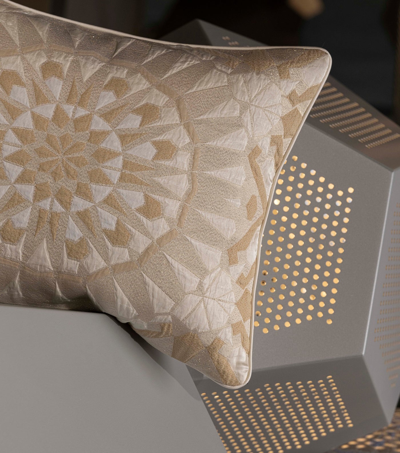 A decorative pillow with a geometric pattern in cream and gold, featuring the Milena Pillow Cover by Celso de Lemos available at Linen Society.