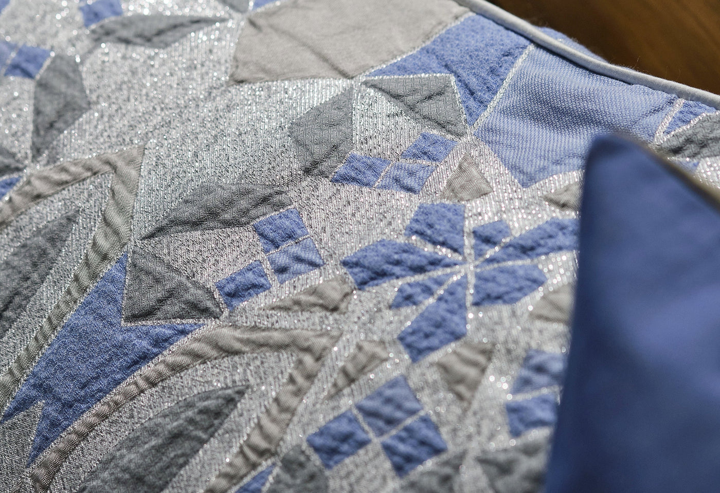 Close-up of a textured blue, grey, and silver geometric patterned pillow cover, featuring Milena Pillow Cover by Celso de Lemos available at Linen Society.