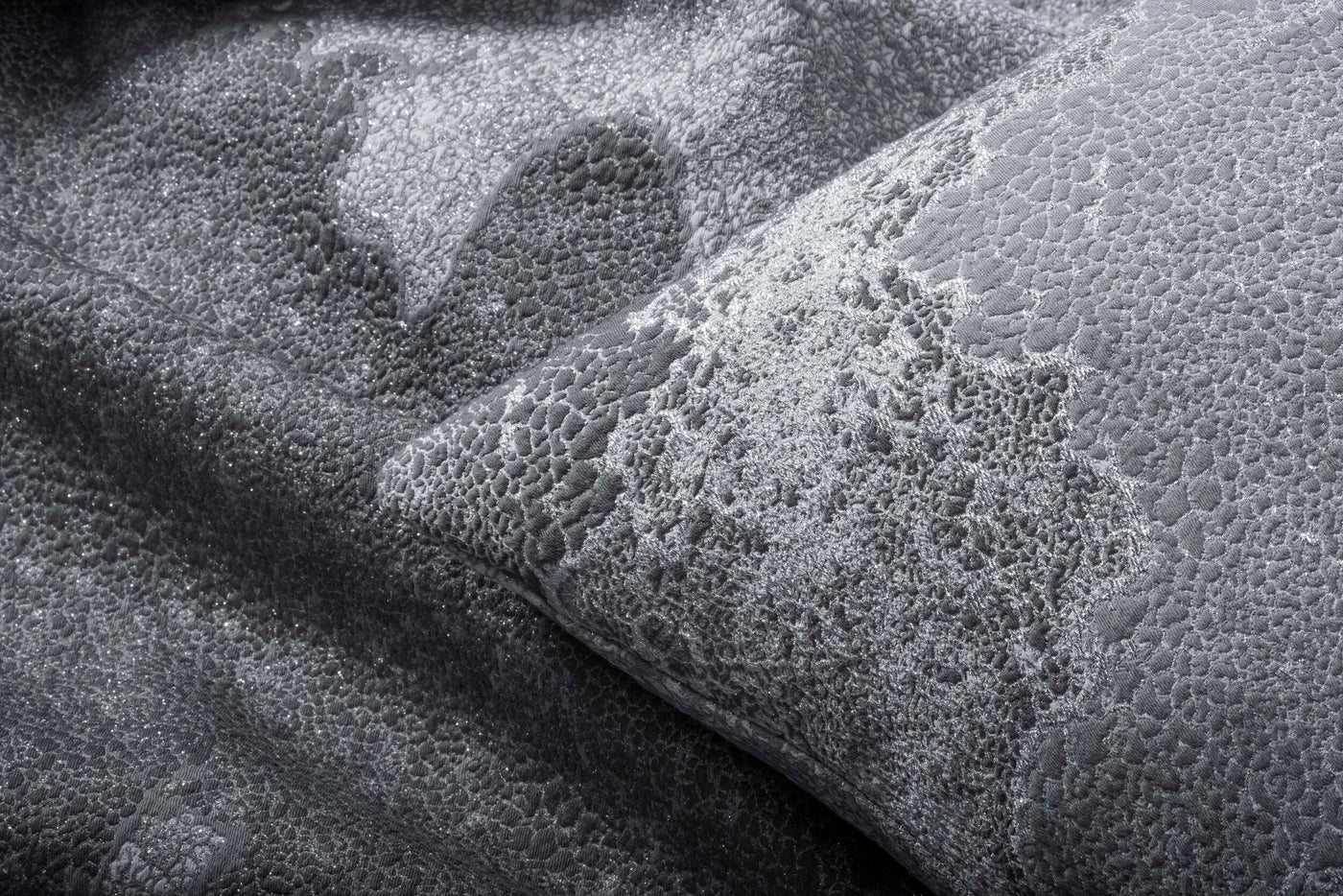 Close-up of a grey textured fabric, featuring the Mundo Pillow Cover by Celso de Lemos available at Linen Society.