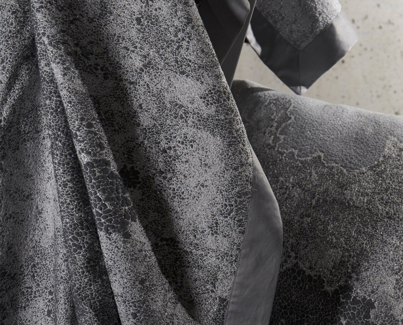 Dark gray pillow cover with a textured, cracked pattern and subtle shimmer, featuring Mundo Pillow Cover by Celso de Lemos available at Linen Society.