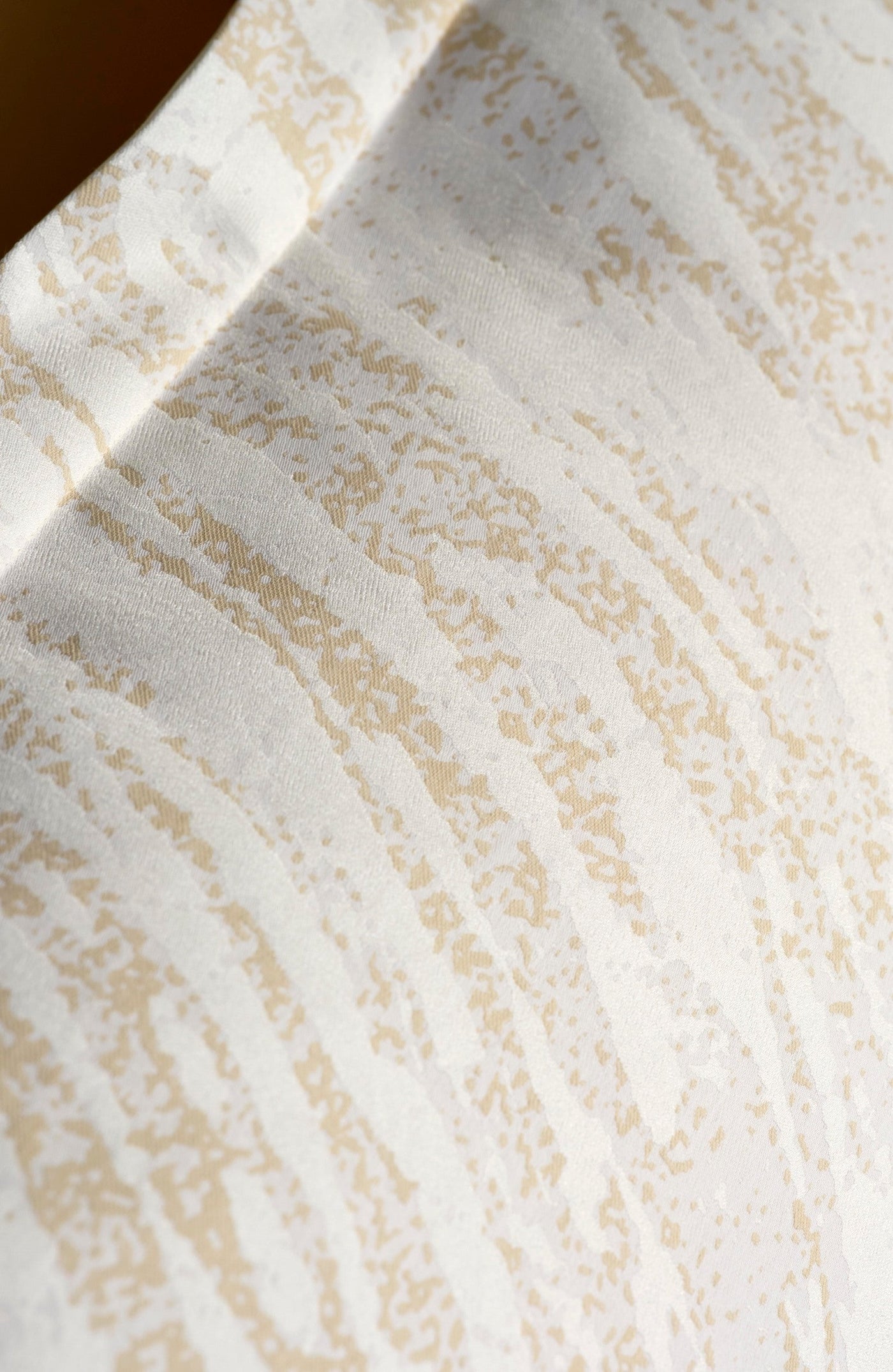 Close-up of ivory and champagne jacquard weave with textured vertical stripe pattern.
