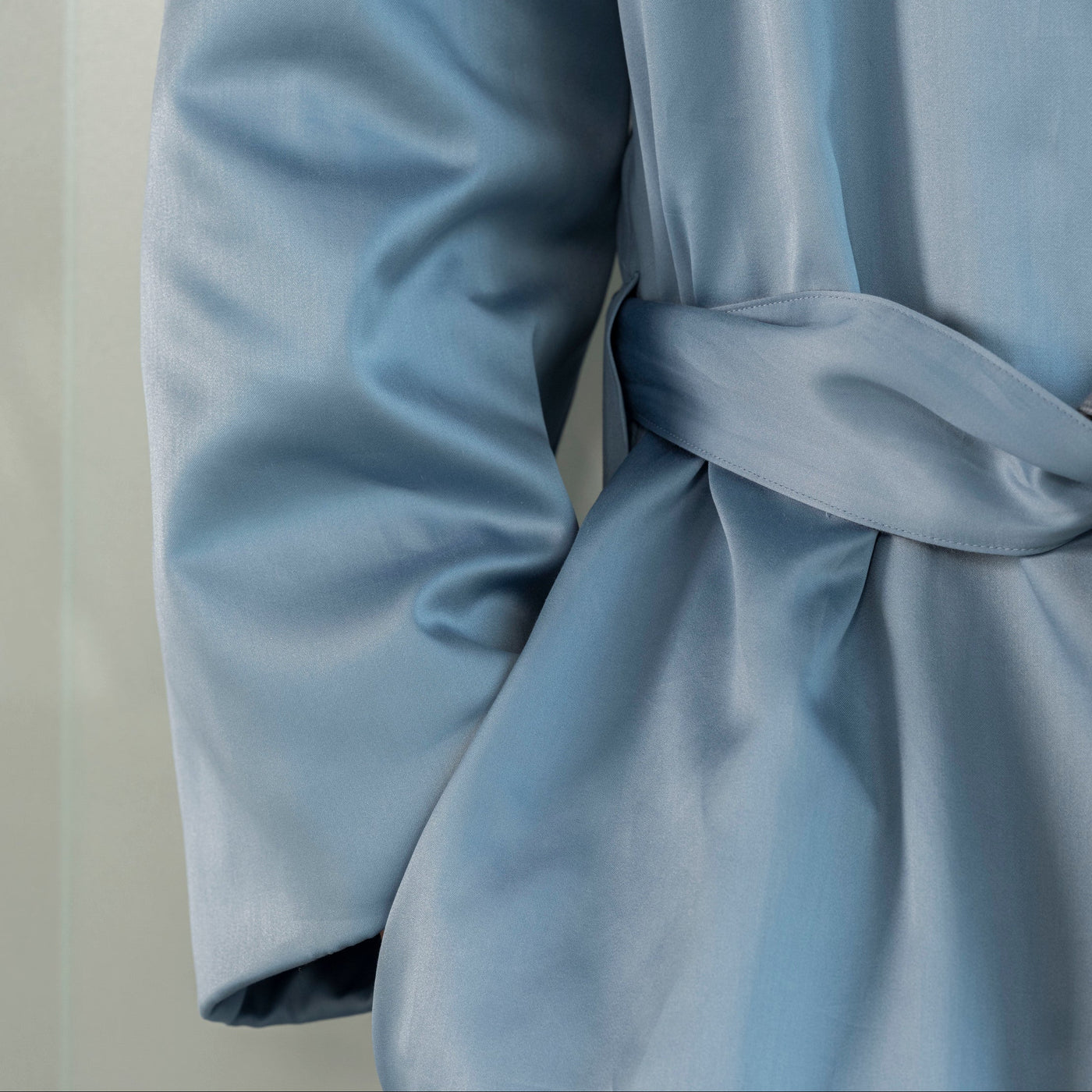 Close-up of a light blue garment with a bow detail on a neutral background
