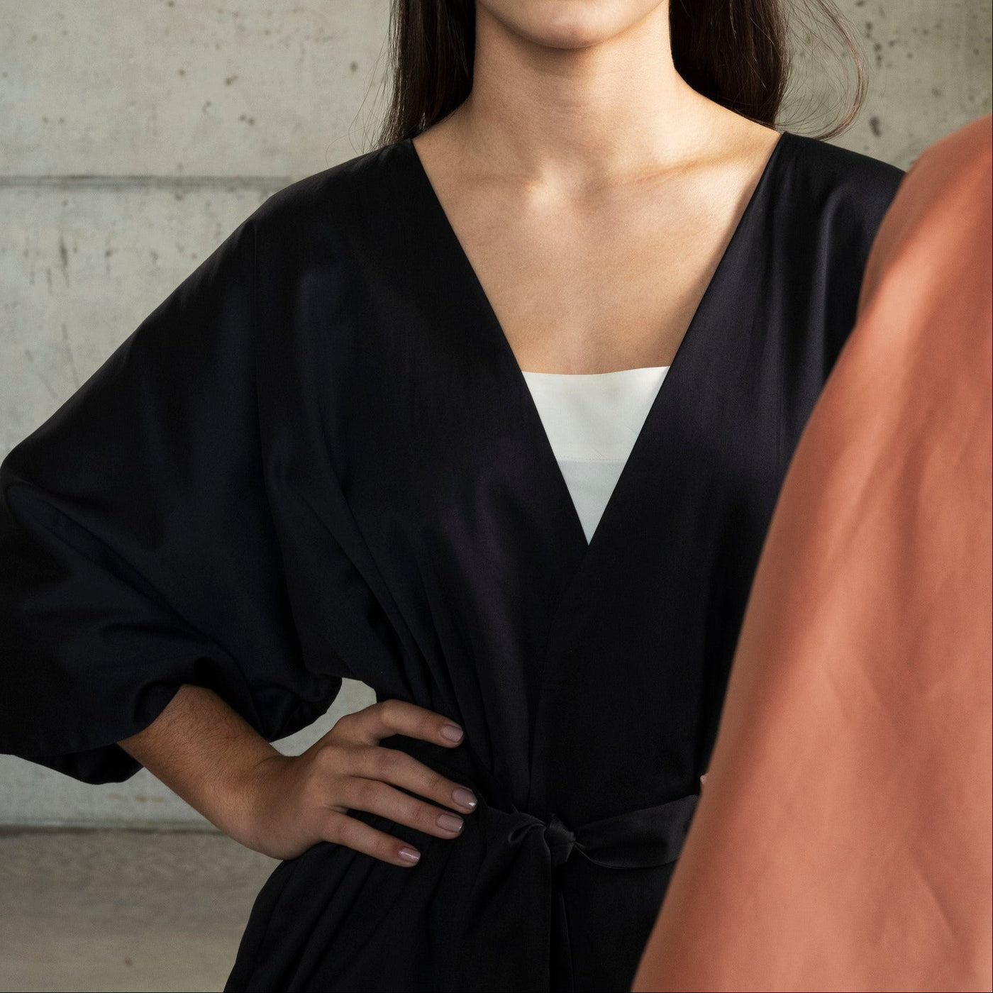 Woman in a black outfit standing against a concrete wall