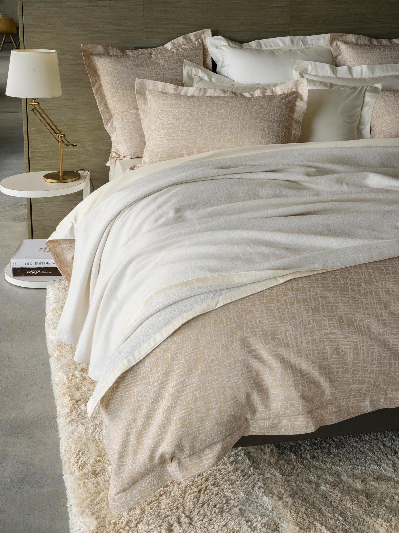 Cream Partition duvet cover draped over bed with ivory throw blanket and gold lamp styling.