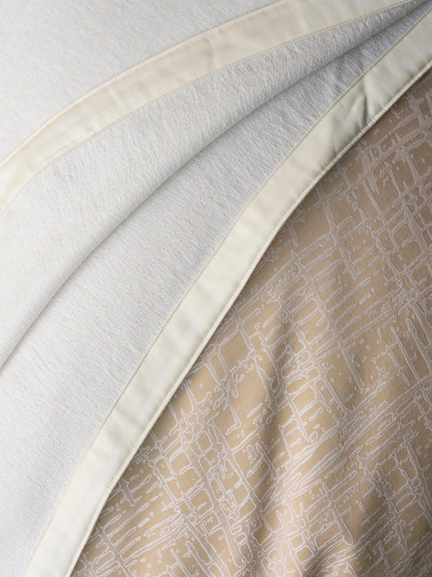 Close-up of ivory satin border trim and tan geometric-print interior lining of Partition duvet cover.