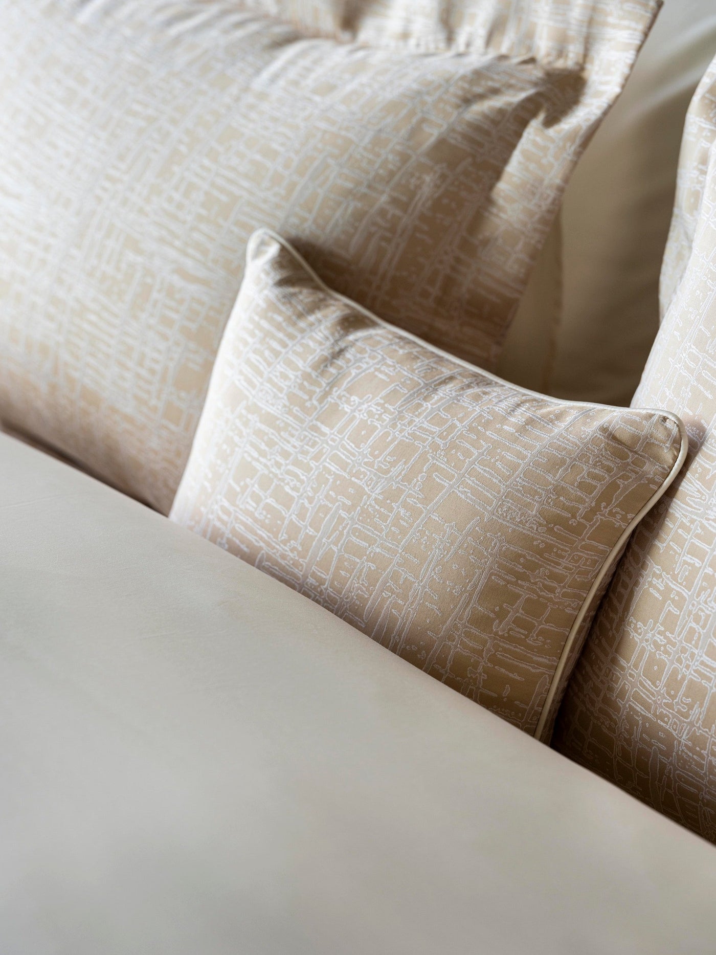 Close-up of Celso de Lemos Partition pillowcase in champagne with white geometric print.